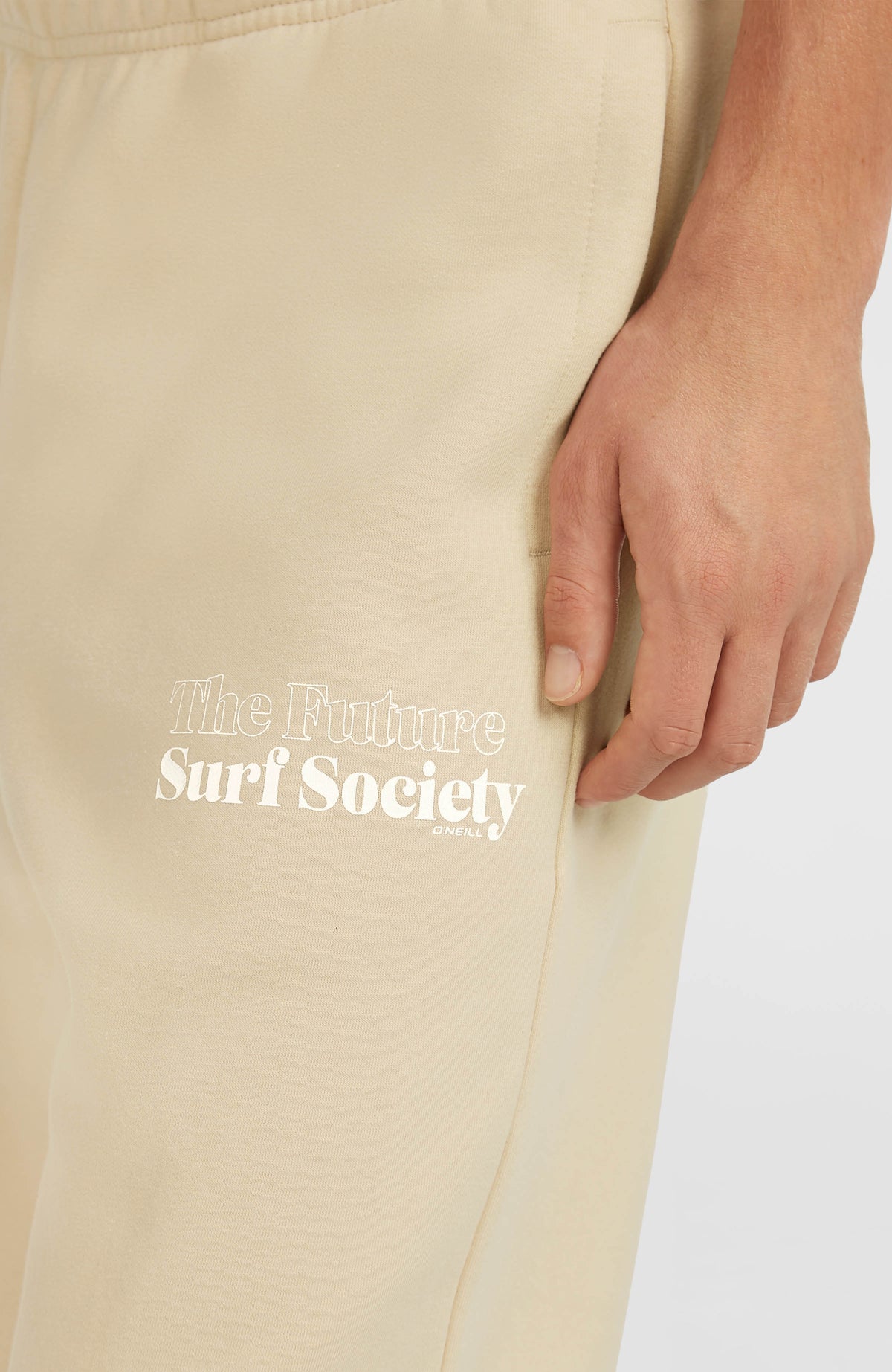 Nahaufnahme des weißen Logo-Prints am oberen Hosenbein der beigen Future Surf Society Jogginghose für Herren