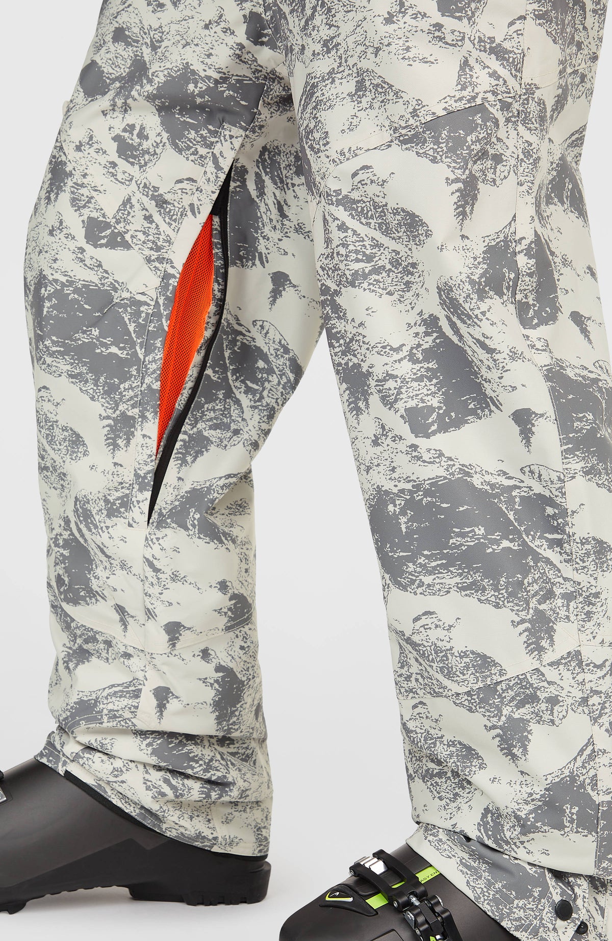 Nahaufnahme des Belüftungsreißverschlusses der grauen FWC'Peak Bib Skihose mit Bergmuster in Weiß