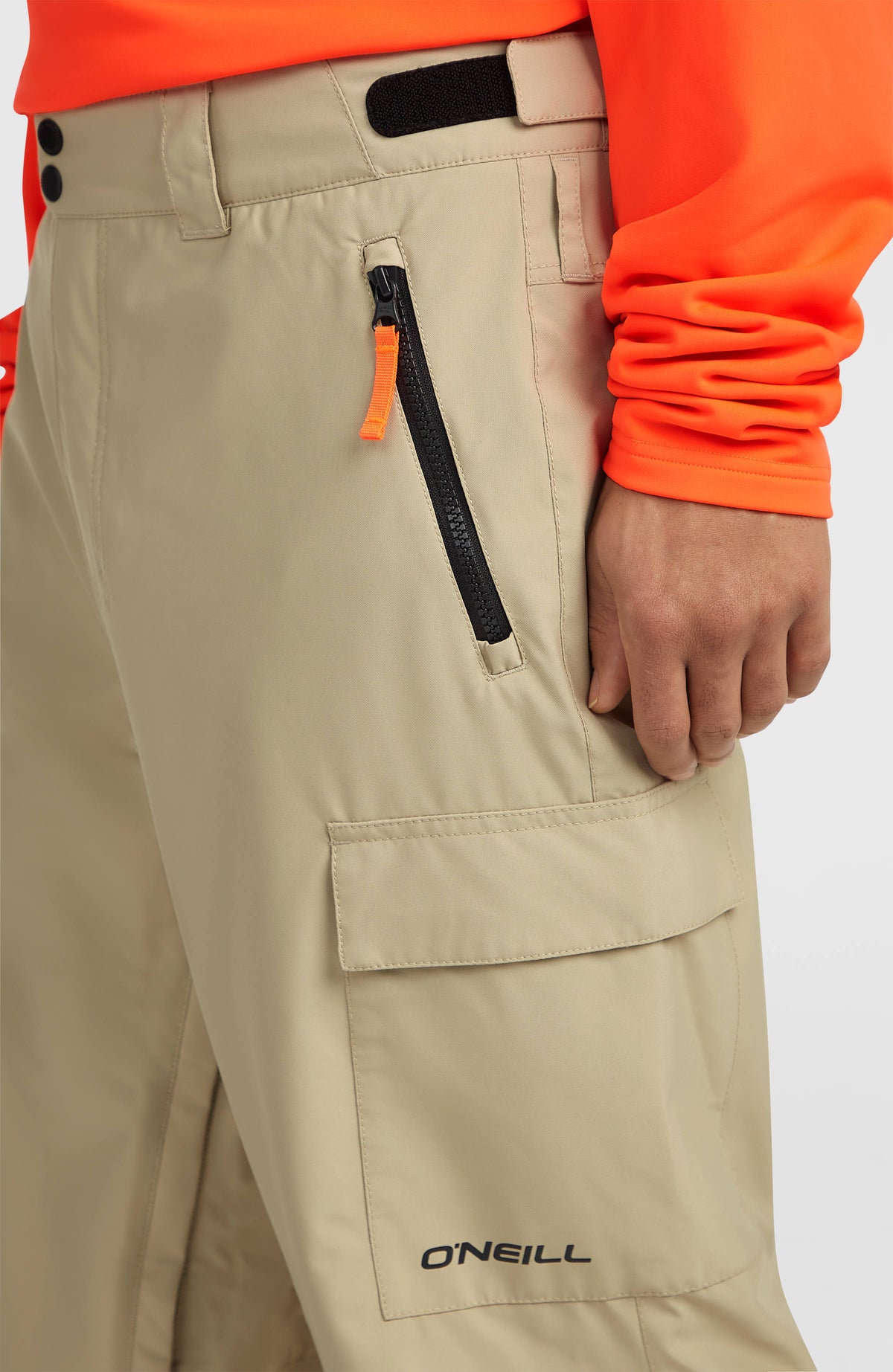 Nahaufnahme der beigen FWC'Cruz Cargo-Skihose am Model, Reißverschlusstasche und Beintasche mit Klappe