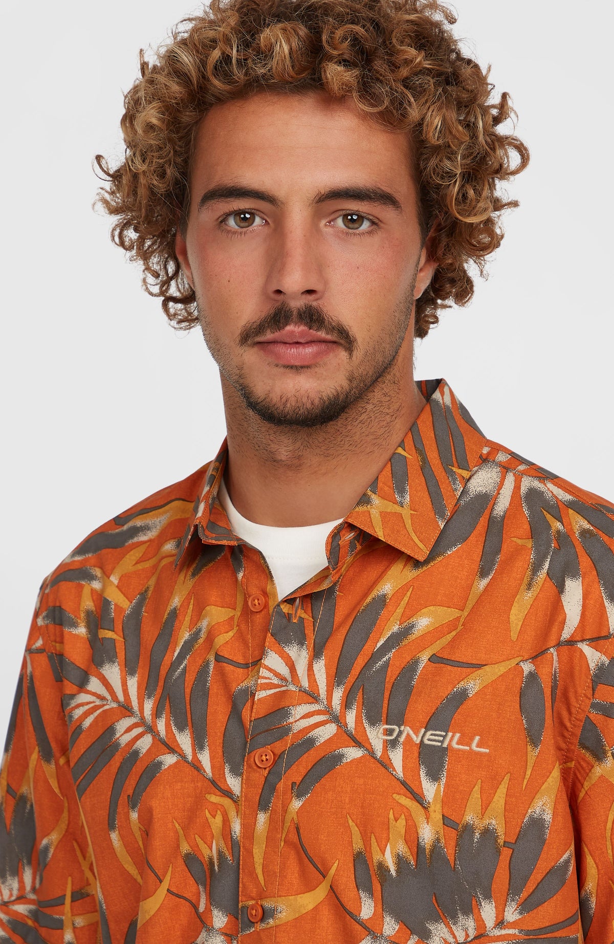 Nahaufnahme von Kragen und Knopfleiste des orangenen Print-Shirts mit Blättermuster in Grau und Gelb