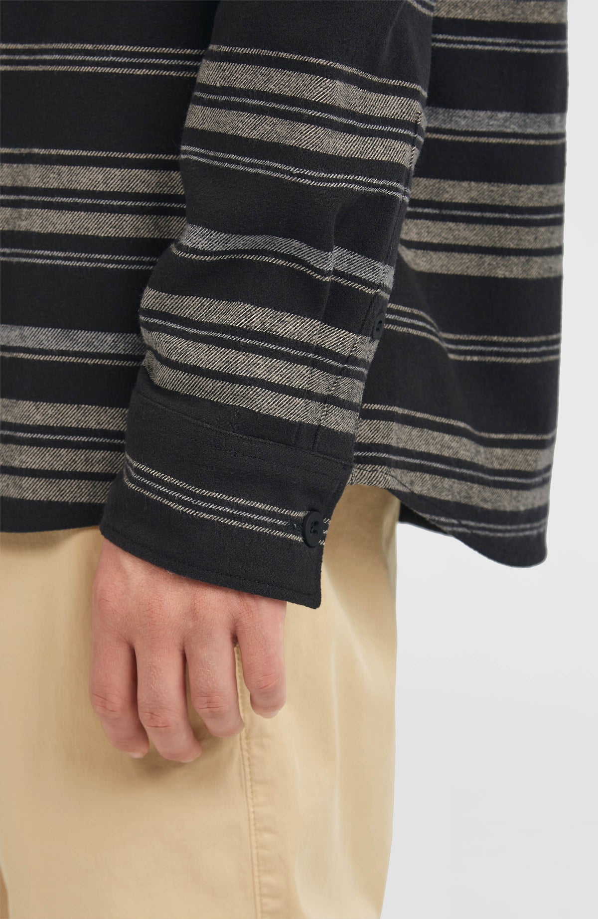 Nahaufnahme der Ärmelmanschette mit Knopf am schwarzen Must-Have Flanellhemd mit Streifenmuster in Grau und Beige