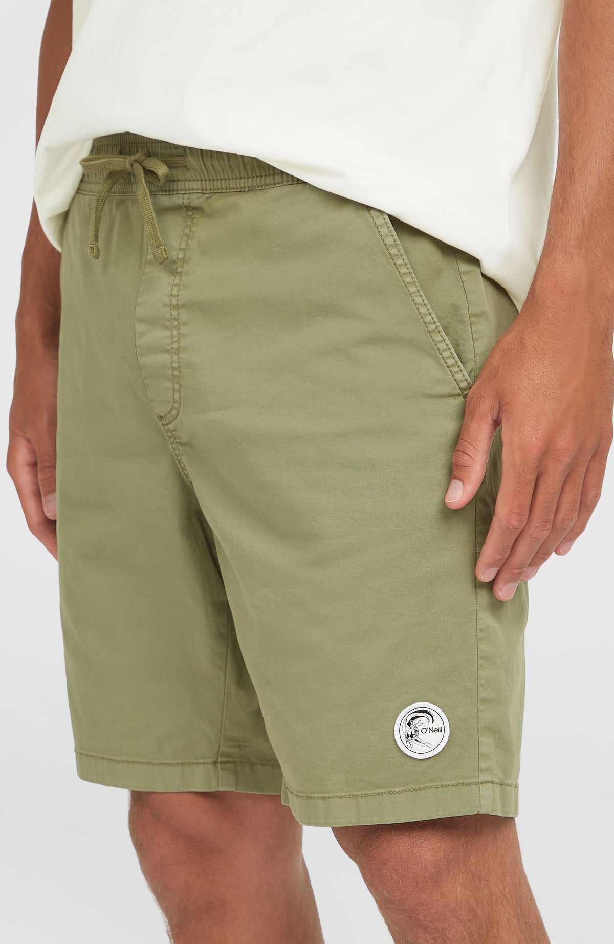 Nahaufnahme der grünen O'Riginals Walk Shorts am Model mit Kordelzug am Bund und rundem Logo-Badge