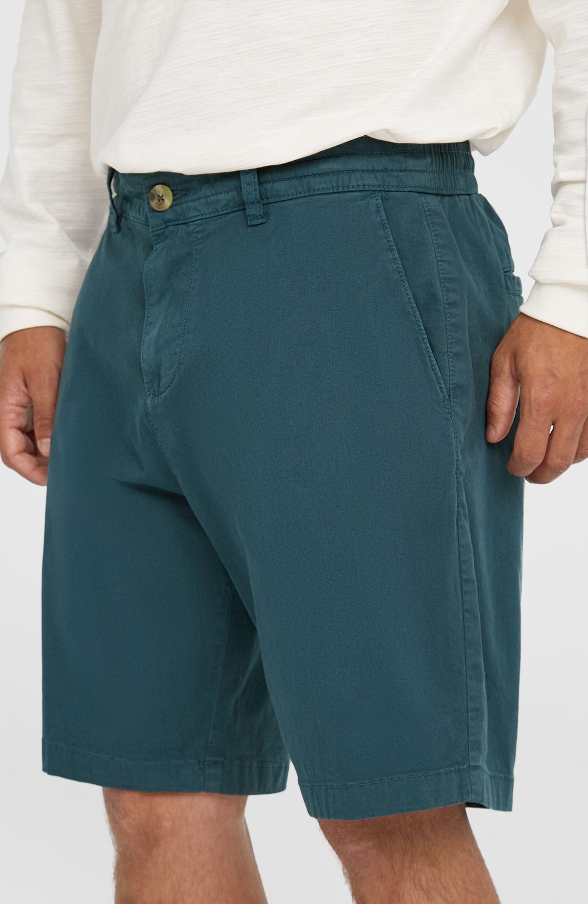 Nahaufnahme der blauen Essentials Chino-Shorts am Model, seitliche Eingrifftasche und elastischer Bund