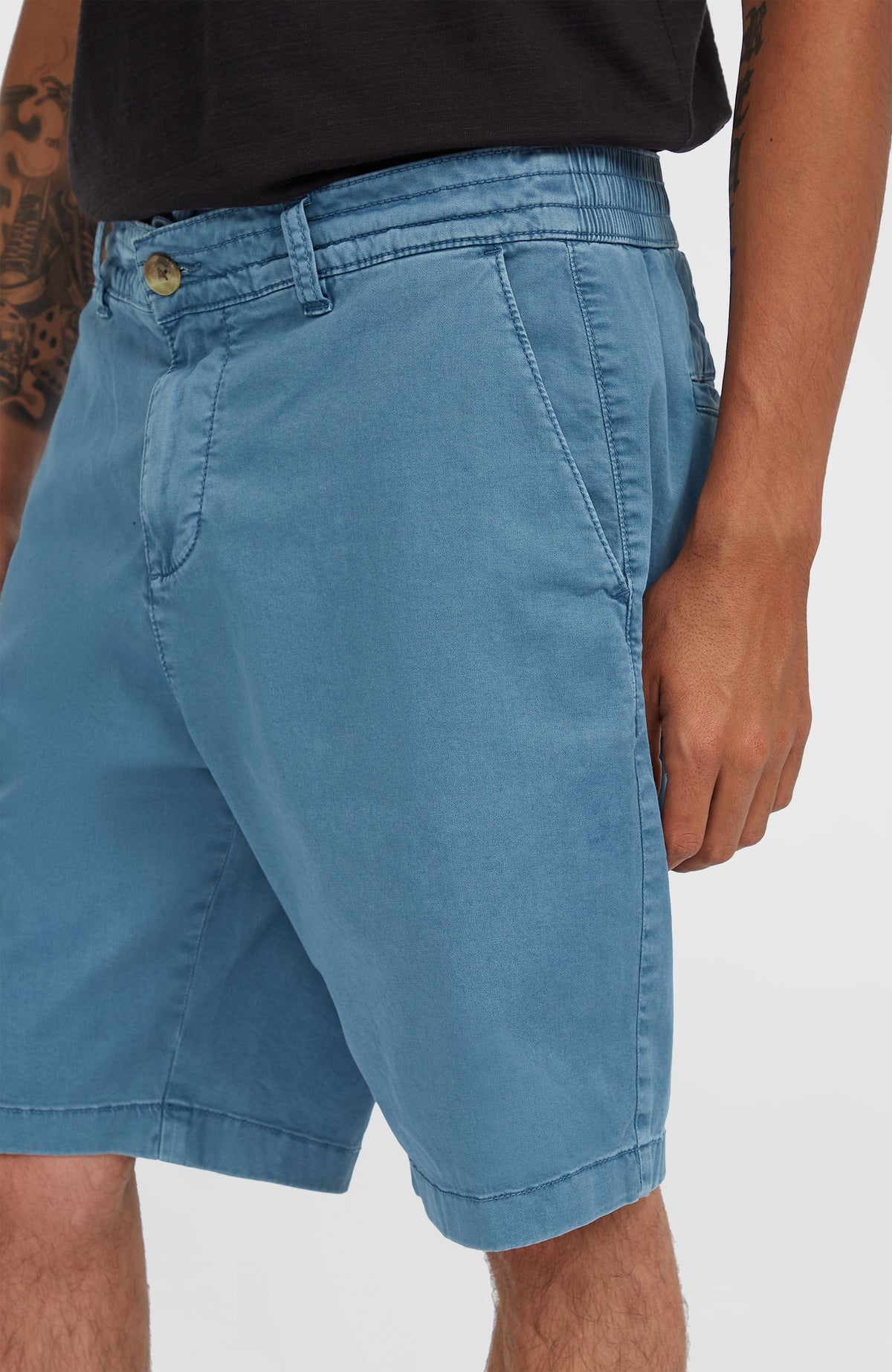 Nahaufnahme der blauen Essentials Chino-Shorts für Herren am Model mit Fokus auf die seitliche Eingrifftasche
