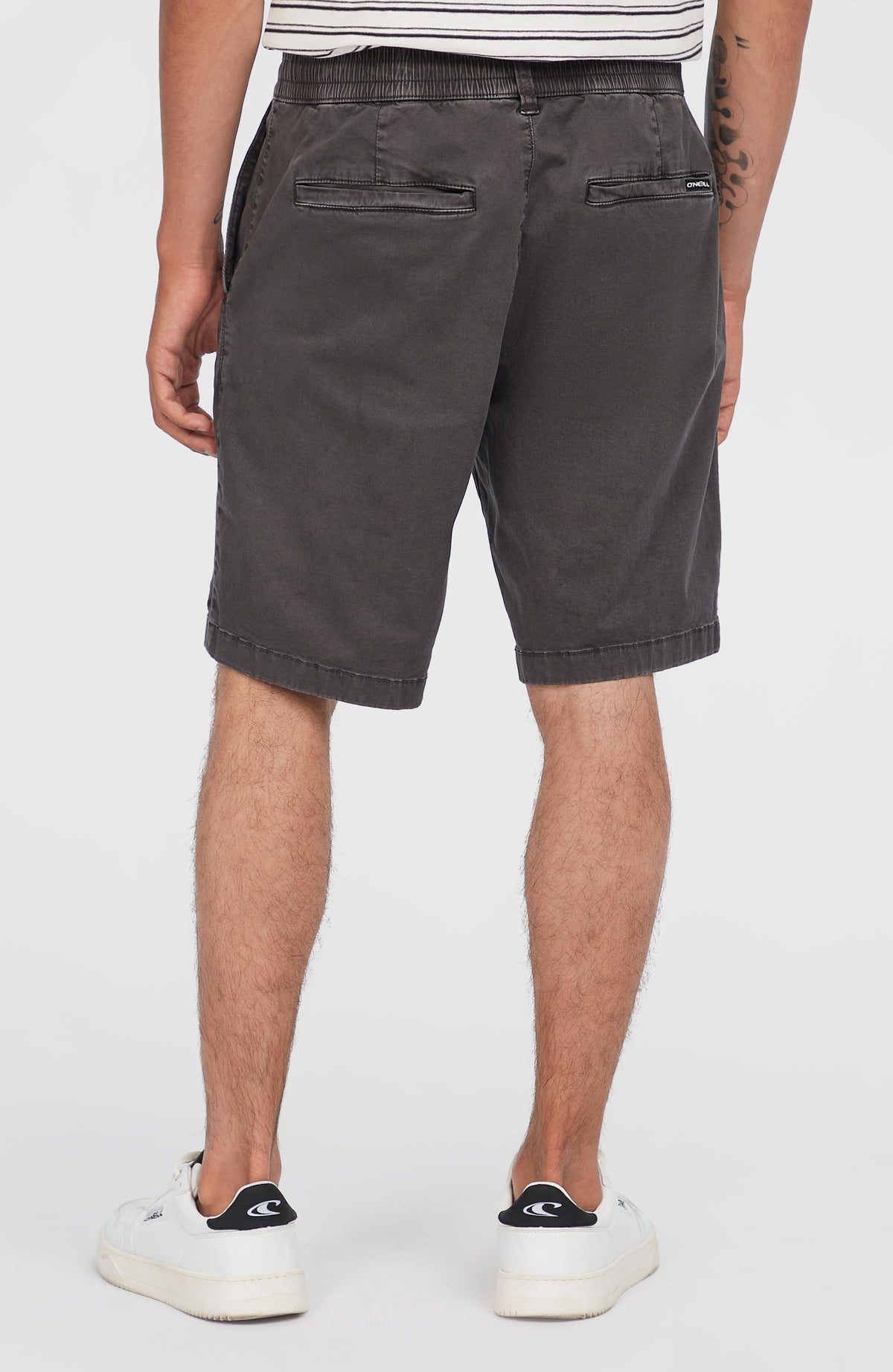 Essentials Chino-Shorts für Herren in Grau, Rückansicht am Model mit Fokus auf die Gesäßtaschen und das Logo-Label