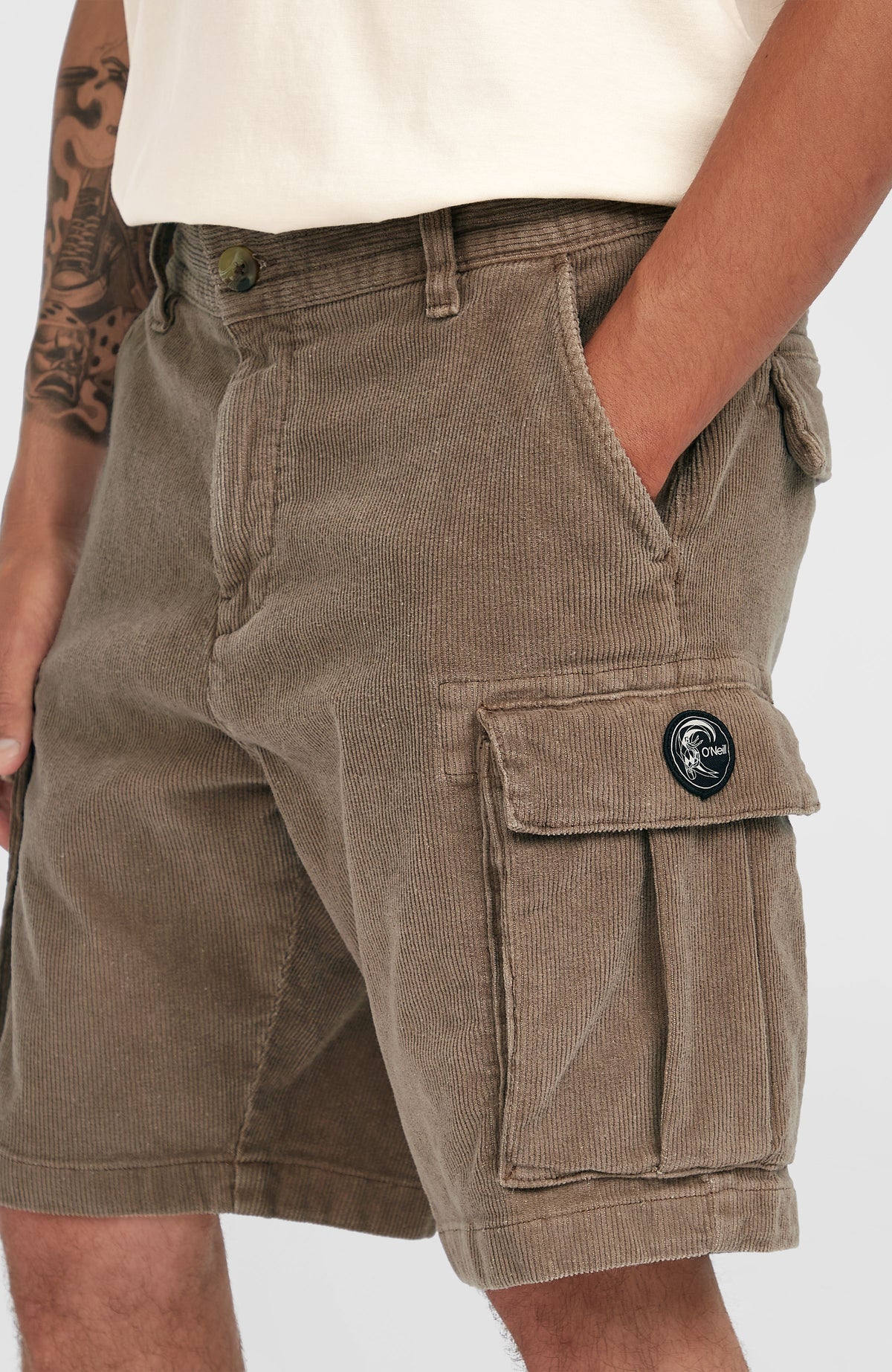 Nahaufnahme der braunen O'Riginals Cord-Cargo-Shorts am Model, aufgesetzte Cargotasche mit Logo-Patch