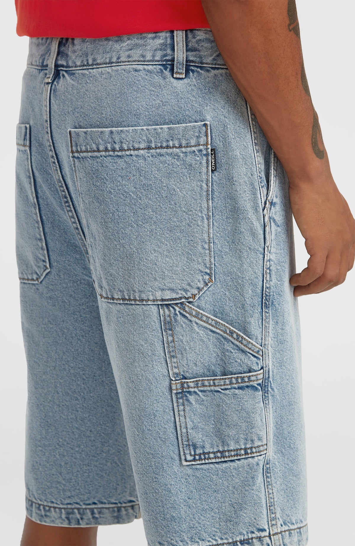 Nahaufnahme der blauen Essentials Jeansshorts am Model, aufgesetzte Gesäßtasche mit kleinem Logo-Label