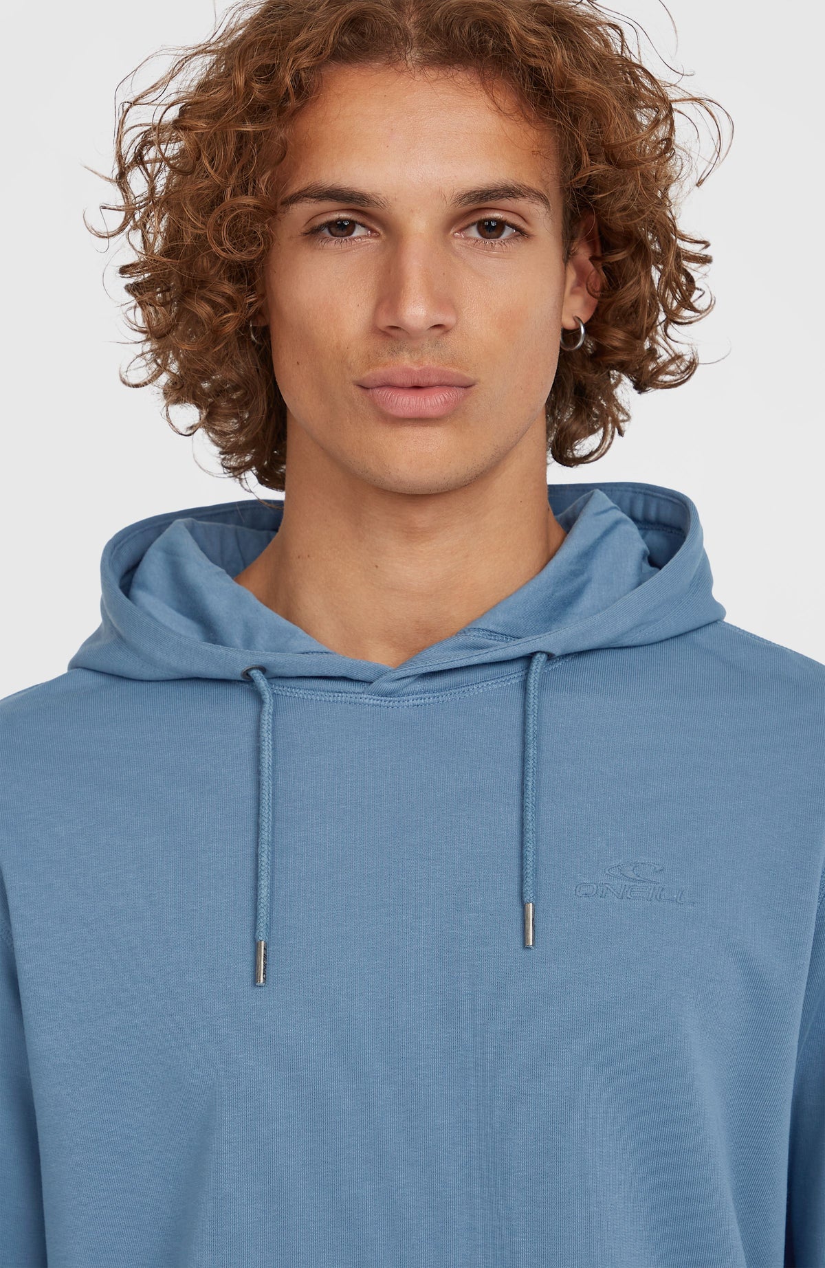 Nahaufnahme des blauen Small Logo Hoodie für Herren am Model mit dezentem Logo-Stick und Kordelzug