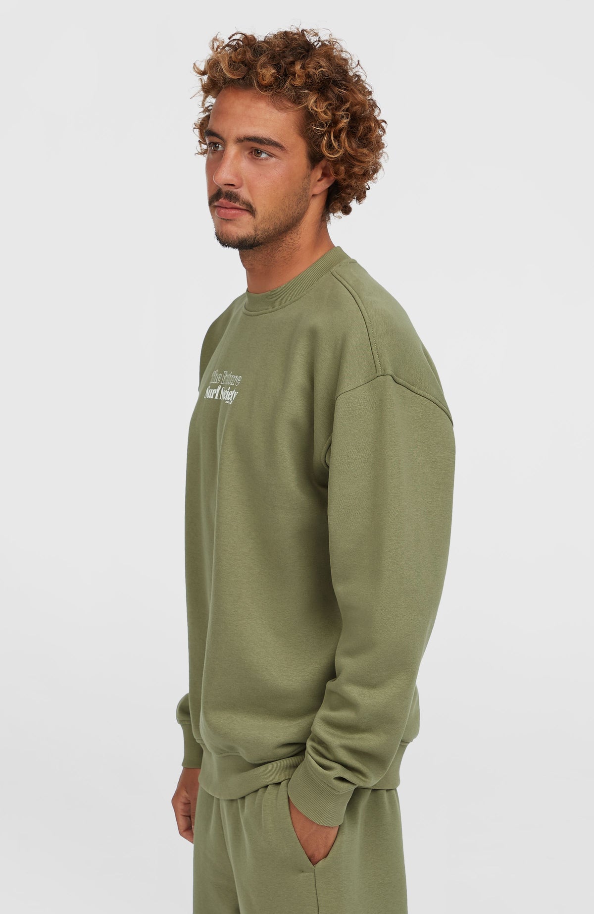 Future Surf Society Crew Sweatshirt für Herren, grün mit Logo-Print in Weiß, getragen am Model in der Seitenansicht
