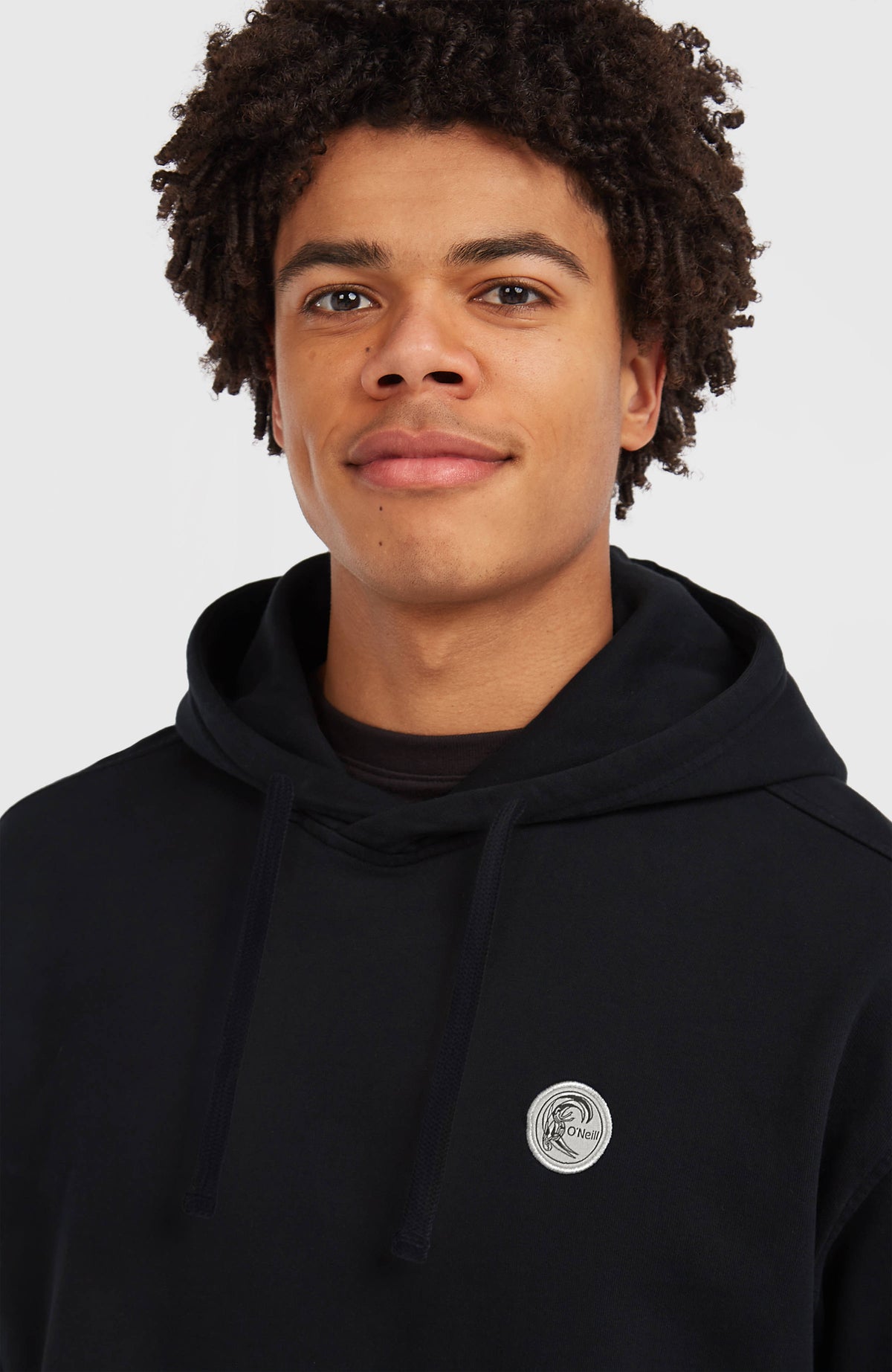 O'Riginals Hoodie für Herren, schwarz mit Grafik-Print in Weiß, Nahaufnahme am Model mit rundem Logo-Badge
