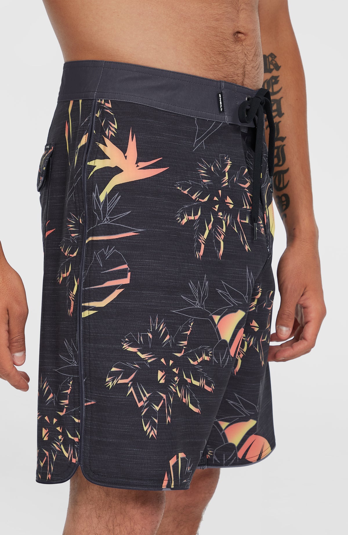 Seitenansicht der schwarzen Hyperfreak Mysto Boardshorts am Model, mit abgerundetem Saum und Palmenmuster
