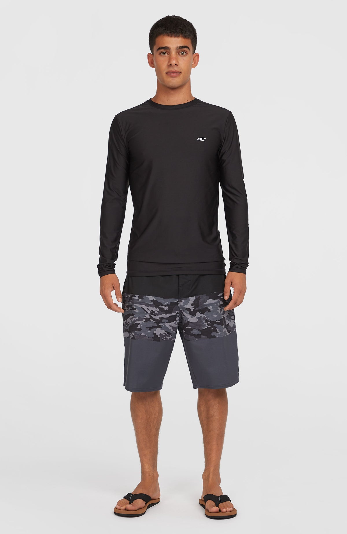 Hyperfreak Heat Block 21'' Boardshorts, schwarz mit Camouflage-Muster in Grau, am Model kombiniert mit Oberteil