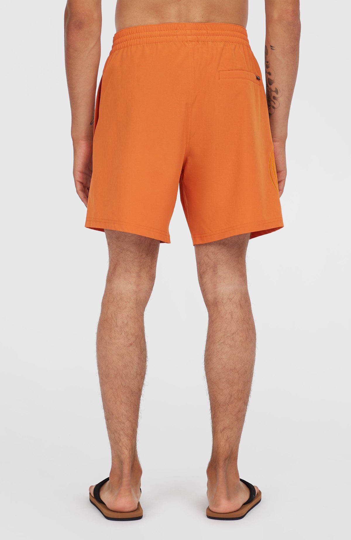 O'Riginals Cali Ocean 16'' Badehose für Herren, orange, getragen am Model von hinten, Rückentasche mit Logo-Fähnchen