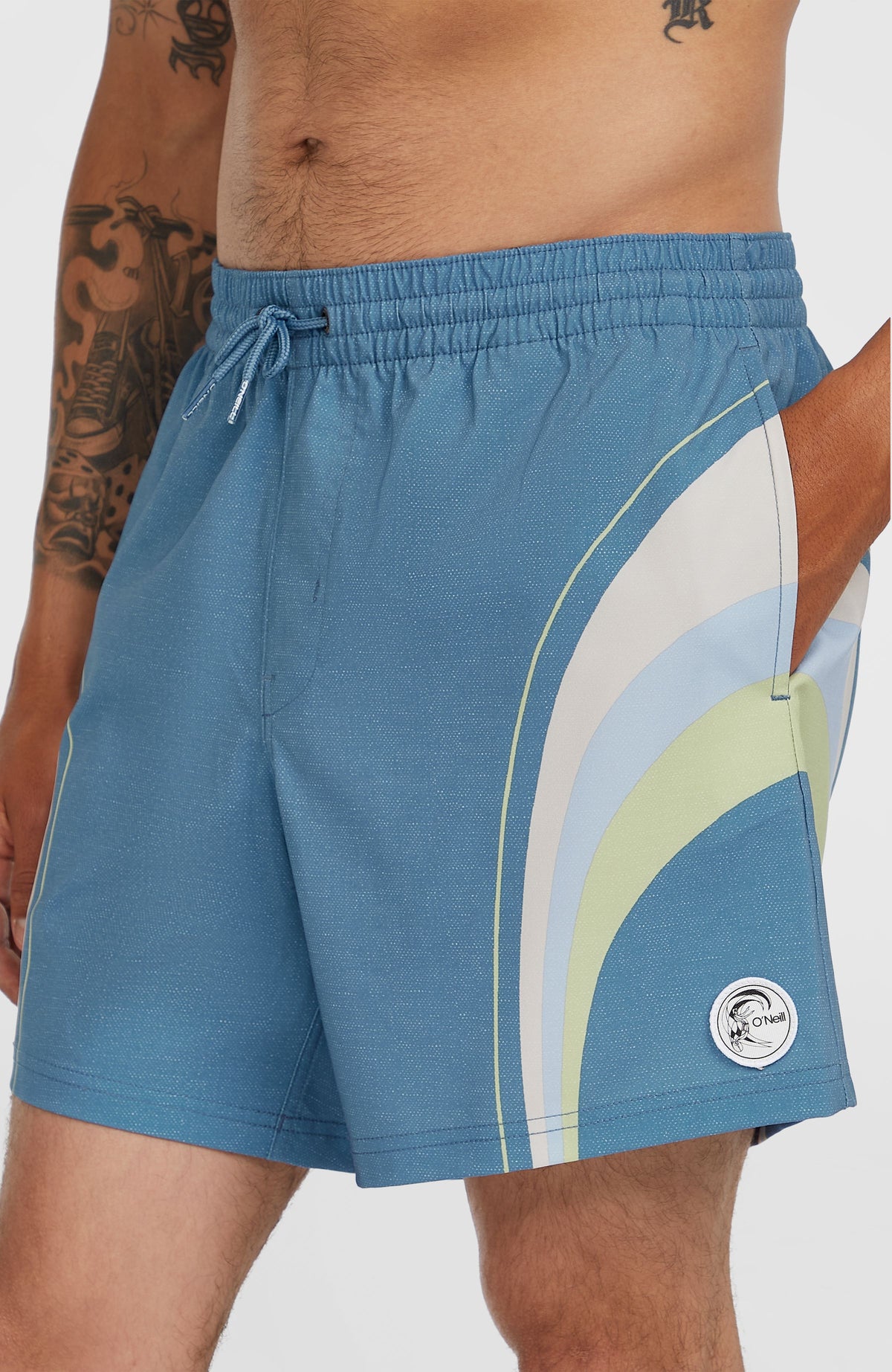 O'Riginals Longboard 15'' Badehose, blau mit Streifenmuster, Nahaufnahme am Model mit Seitentasche und Logo-Badge