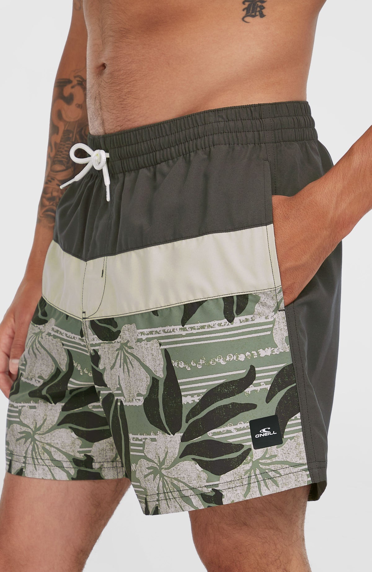 Cali Block 15'' Badehose für Herren, grün mit Blumenmuster in Weiß, Nahaufnahme mit Seitentasche und Logo-Patch