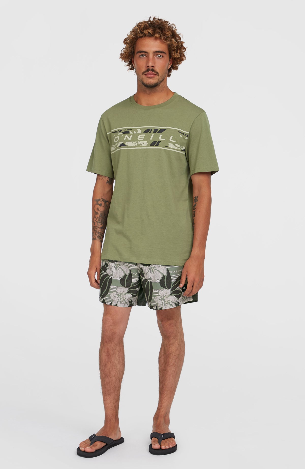 Cali Block 15'' Badehose für Herren, grün mit Blumenmuster in Weiß, getragen am Model in der Ganzkörperansicht