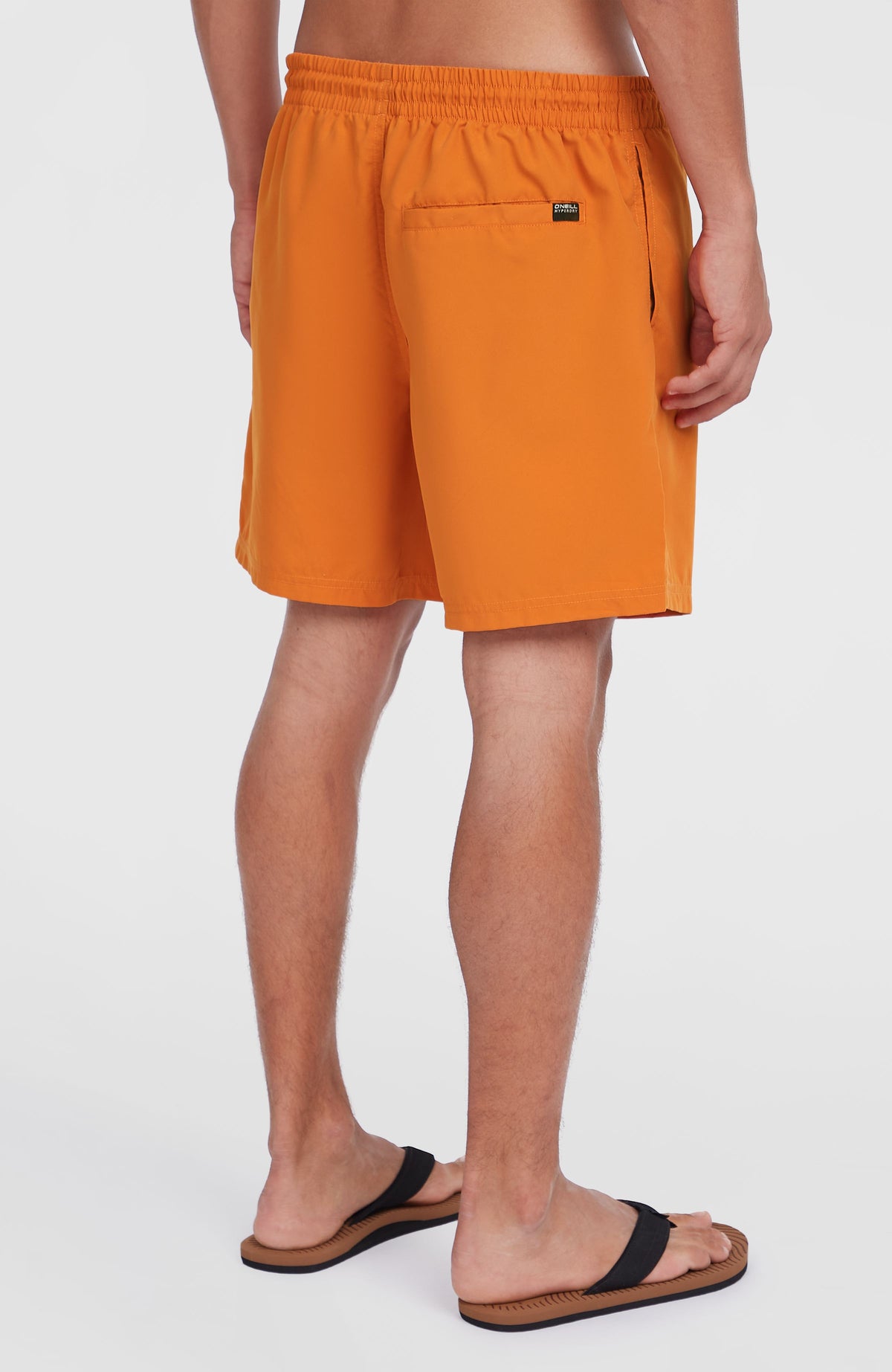 Cali 16'' Badehose für Herren, orange mit Logo-Print in Weiß, Rückansicht am Model mit Rückentasche