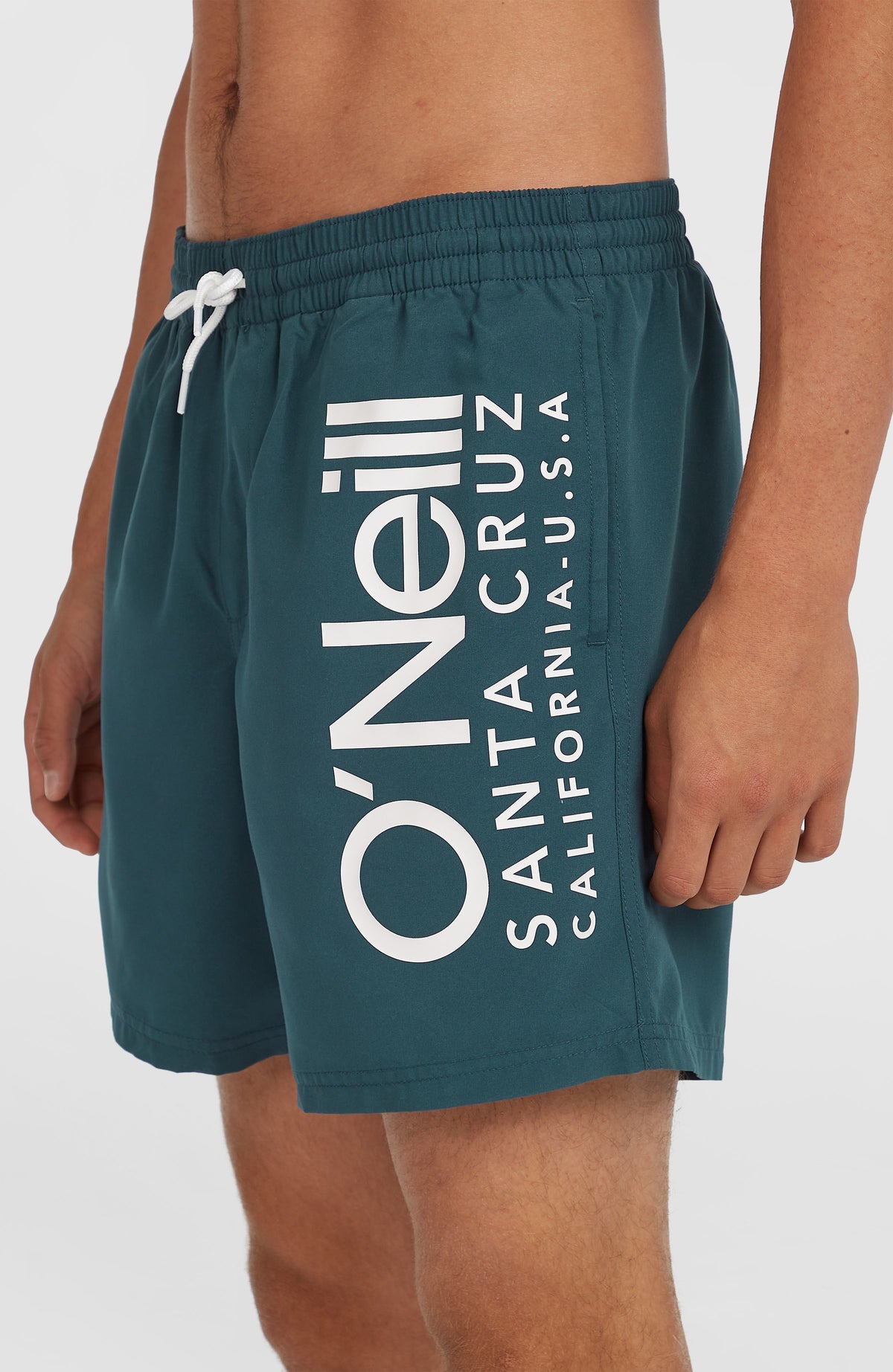Nahaufnahme der blauen Original Cali 16'' Badehose am Model, seitlicher Logo-Print in Weiß