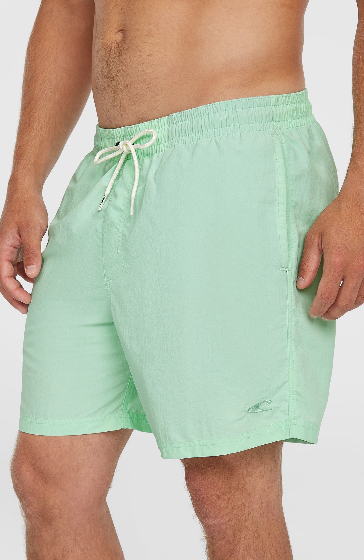 Vert 16'' Badehose für Herren, grün, Seitenansicht am Model mit seitlicher Eingrifftasche und Logo-Stickerei