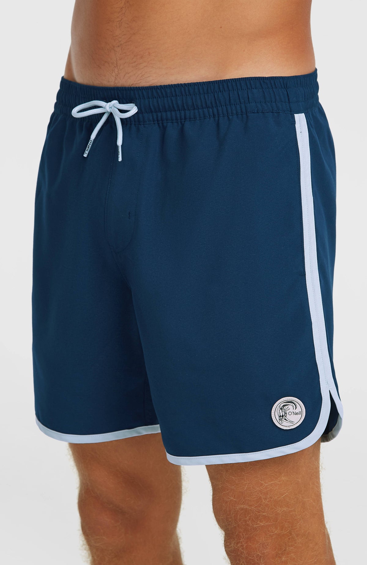 O'Riginals Scallop 16'' Badehose, blau, Nahaufnahme der Seite mit rundem Logo-Patch und Saumeinfassung