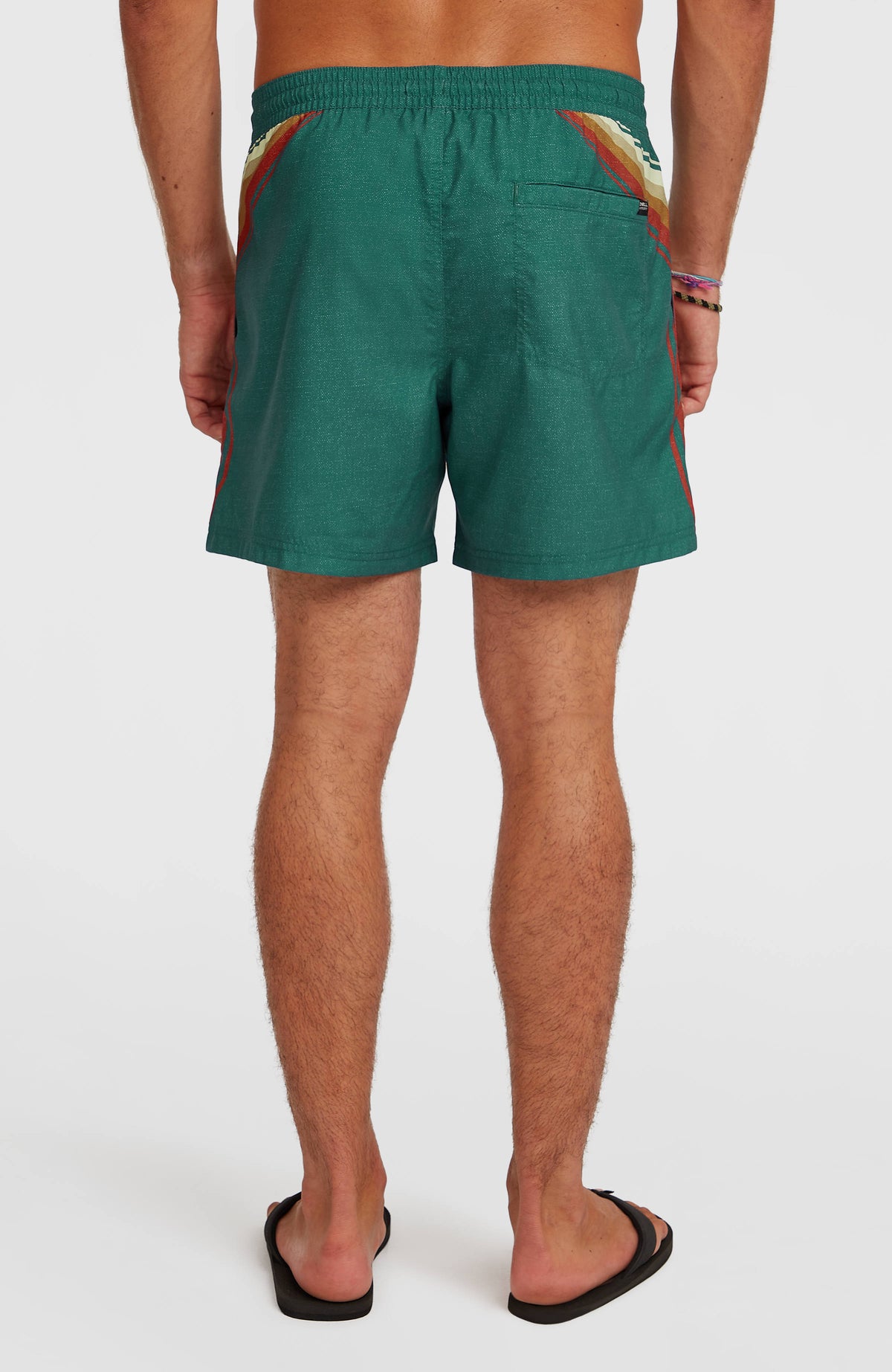 O'Riginals Longboard 15'' Badehose, grün mit Streifenmuster in Beige und Orange, am Model von hinten, Gesäßtasche rechts