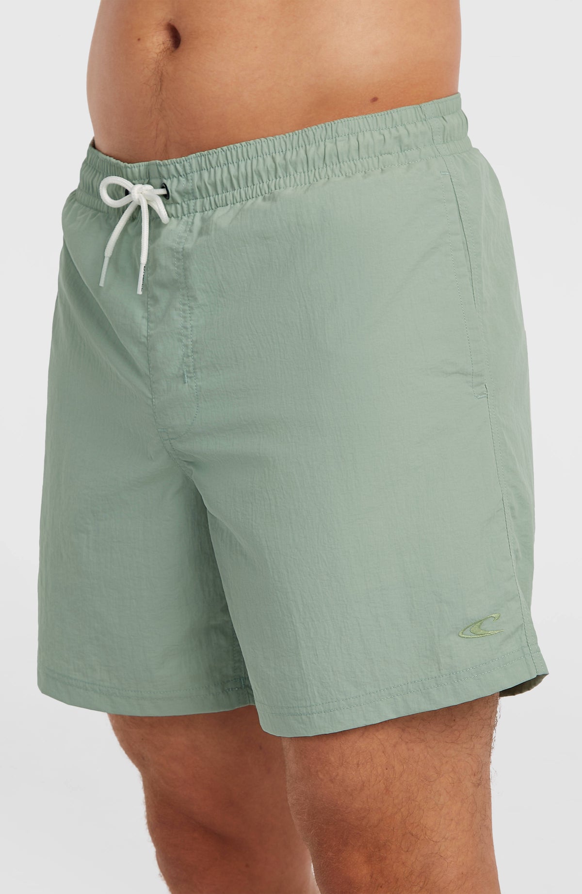 Vert 16'' Badehose für Herren, grün, Nahaufnahme am Model mit Kordelzug am Bund und Logo-Stickerei am Saum