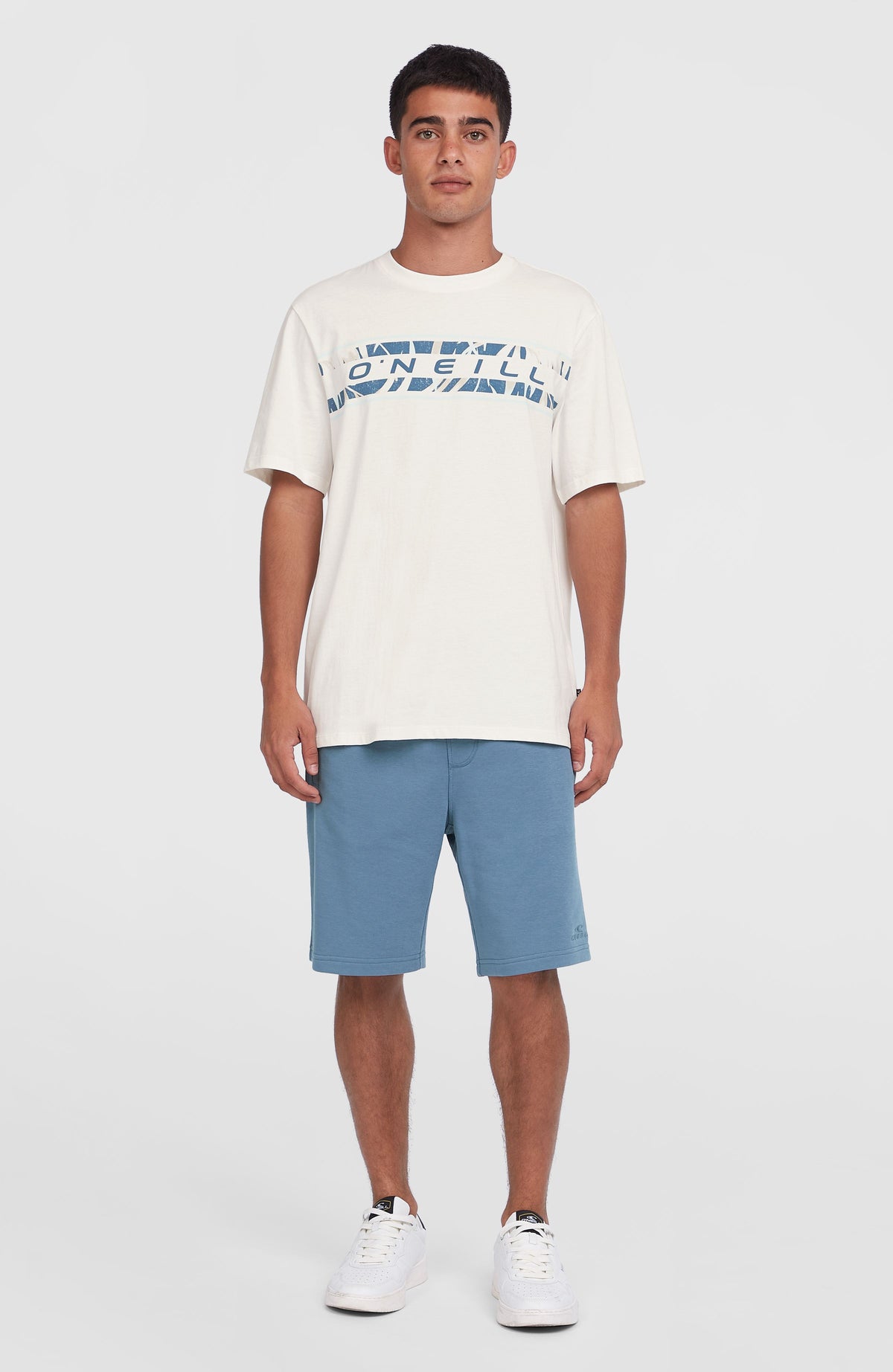 Front Graphic T-Shirt für Herren, weiß mit Logo-Print in Blau, getragen am Model in Ganzkörperansicht mit Shorts