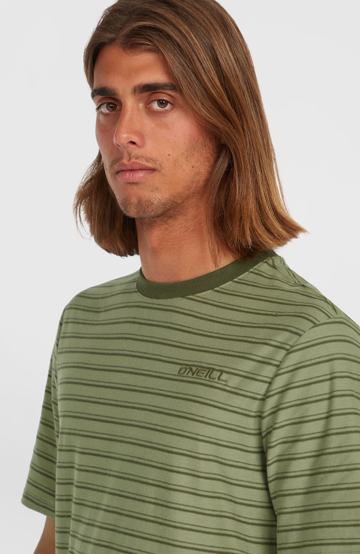 Nahaufnahme des Yarn Stripe T-Shirt in Grün mit Streifenmuster in Dunkelgrün, gestickter Logo-Schriftzug
