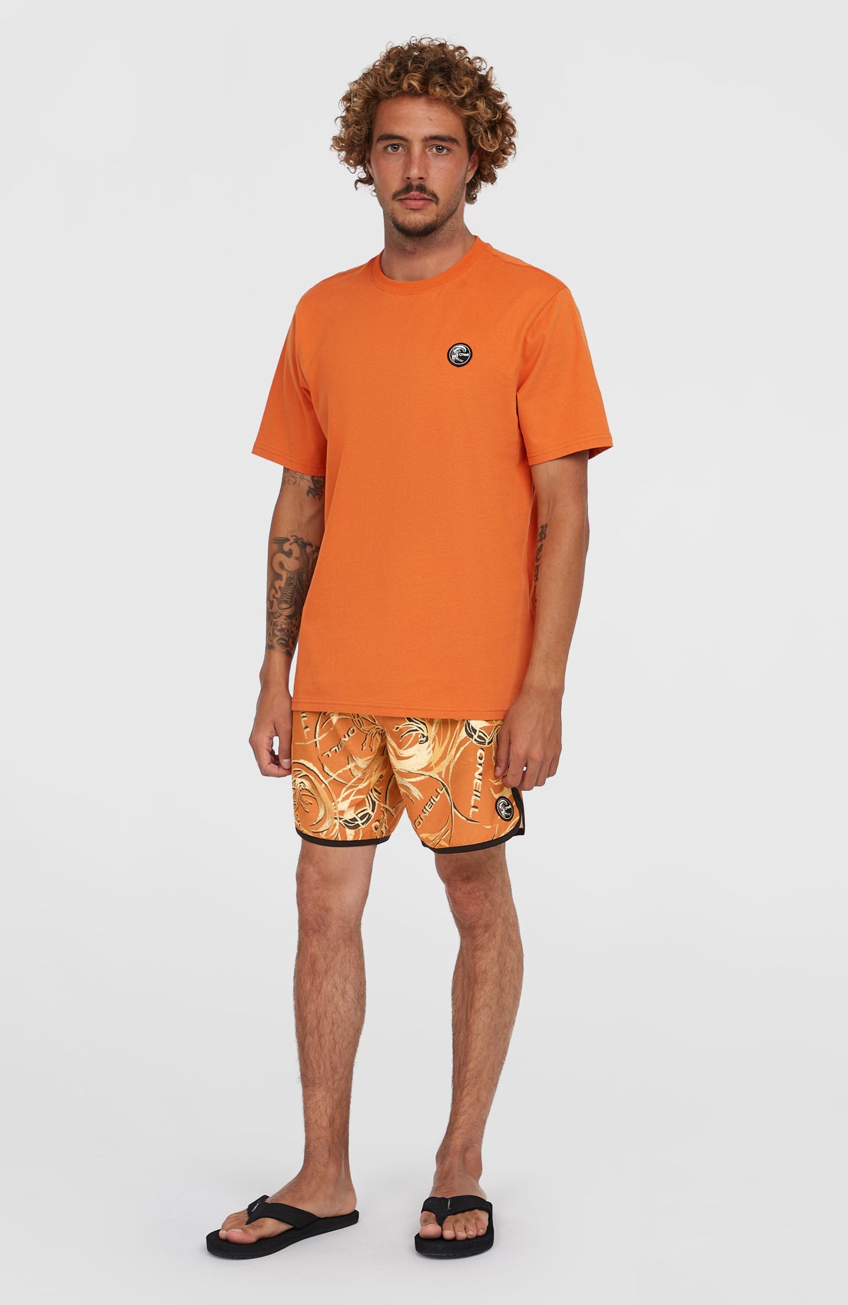 O'Riginals Badge T-Shirt für Herren, orange, Ganzkörperansicht am Model von vorne in Kombination mit Shorts