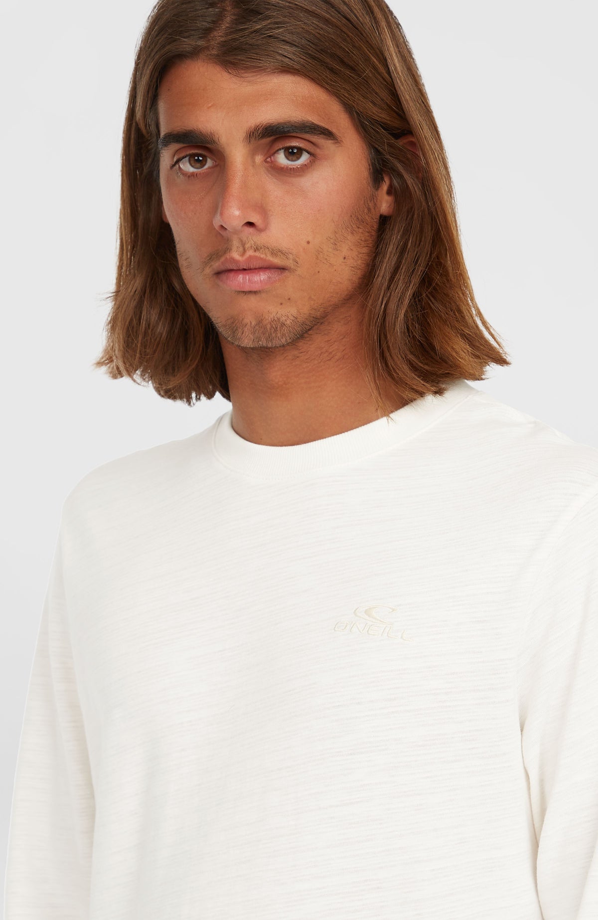 Nahaufnahme des weißen Slub Langarmshirts mit dezentem Logo-Stick auf der Brust, am Model