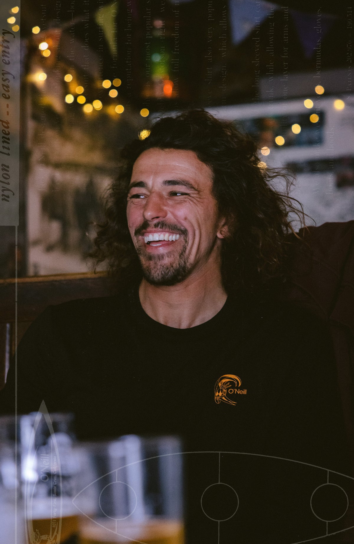 O'Riginals Hybrid Langarmshirt für Herren, schwarz mit Logo-Print in Orange, in einem Restaurant
