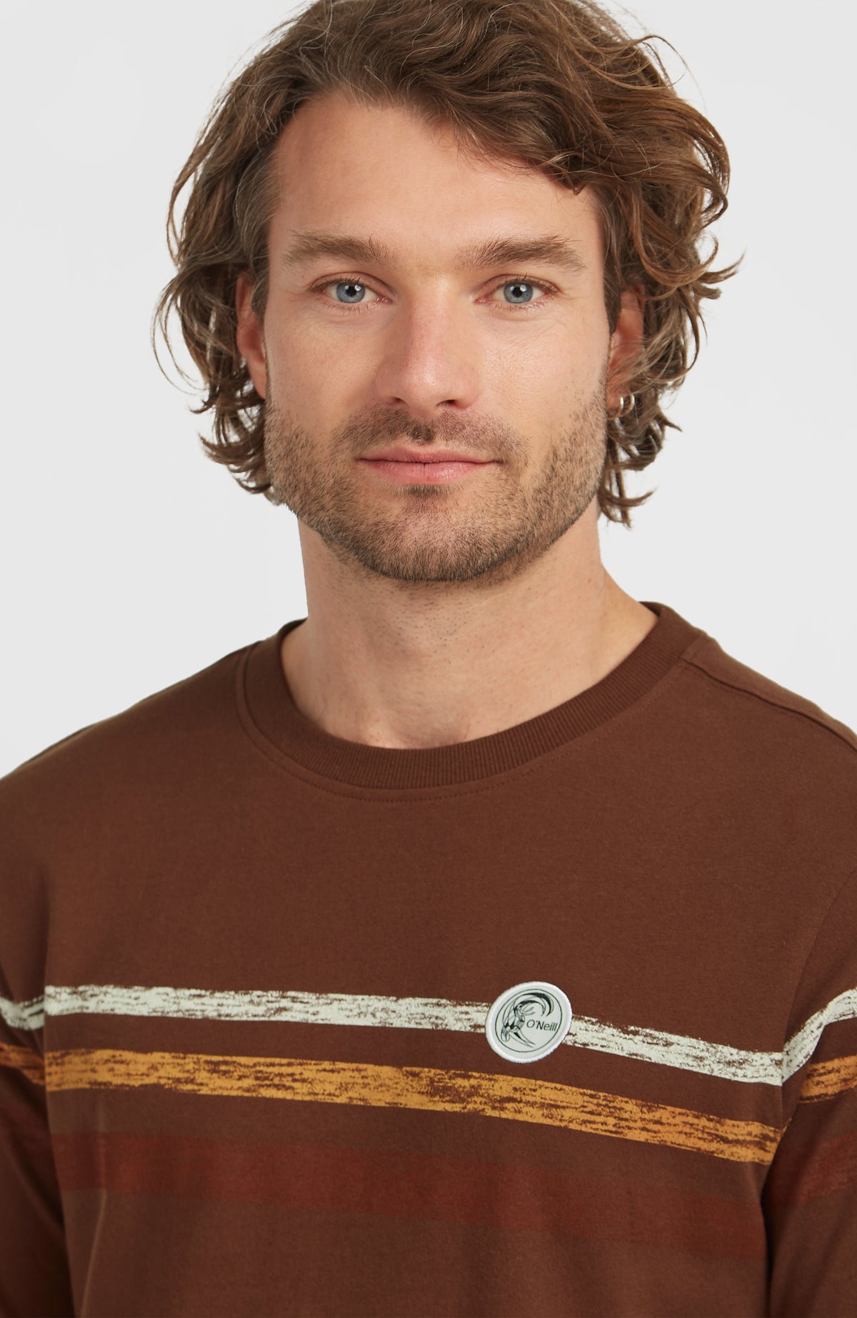 Nahaufnahme des braunen O'Riginals Stripe T-Shirt mit Streifenmuster in Weiß und Gelb und rundem Logo-Badge
