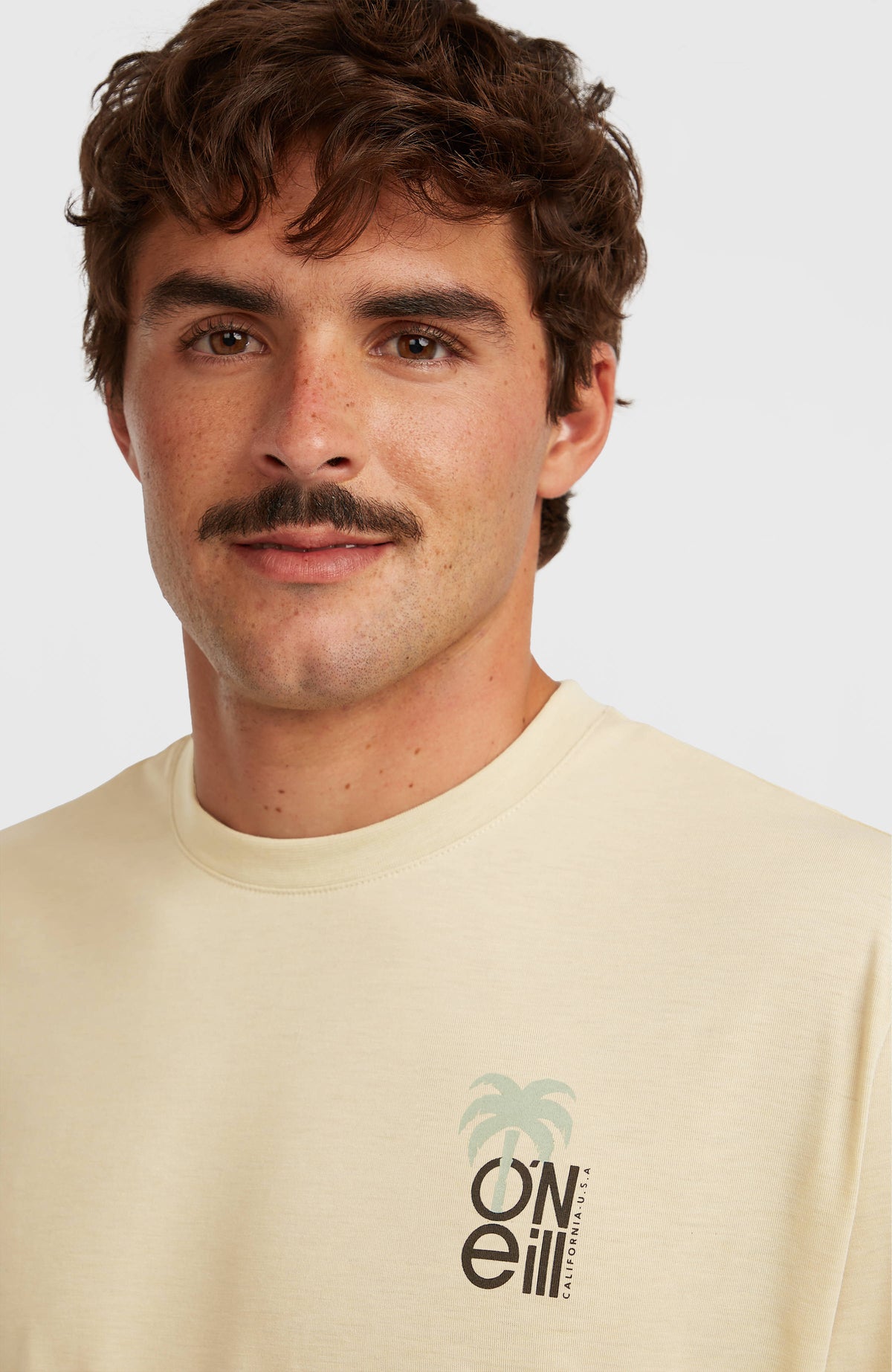 Nahaufnahme von Rundhalsausschnitt und Logo-Print des beigen Hybrid Polygiene Graphic T-Shirts am Model