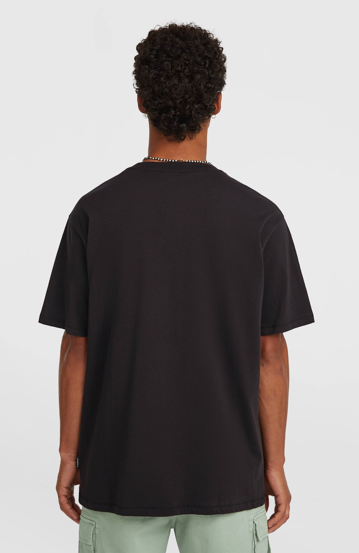 Logo Stripe T-Shirt für Herren, schwarz, getragen am Model, Rückansicht mit kleinem Logo-Label am Saum