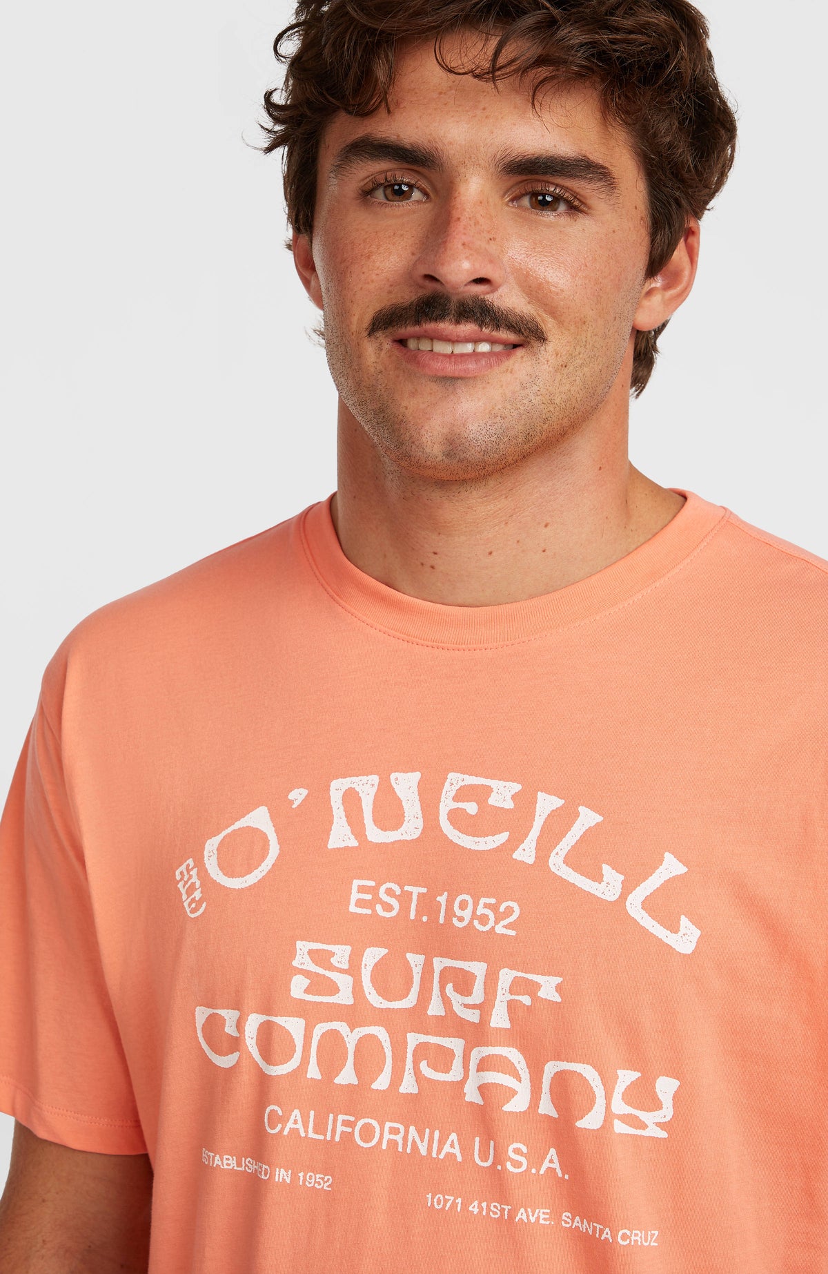 Muir T-Shirt, orange, Nahaufnahme des Rundhalsausschnitts mit Logo-Print in Weiß am Model