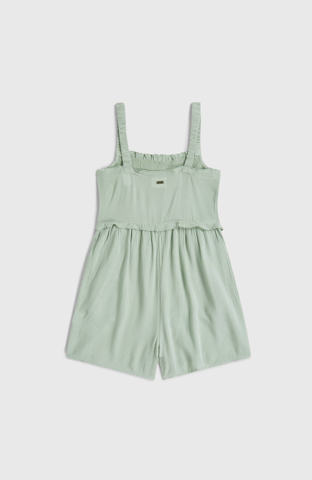 Grüner Woven Playsuit für Mädchen, flach liegend von hinten mit dezenter Logo-Plakette am Bund