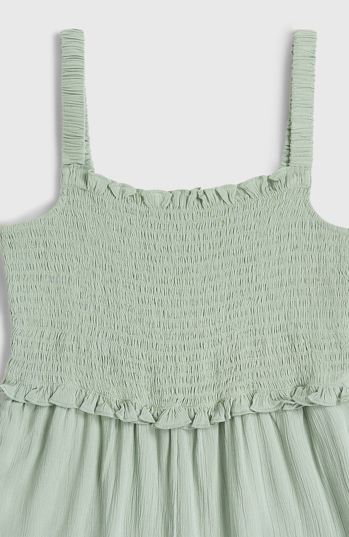 Nahaufnahme des grünen Woven Playsuit, flach liegend mit elastischem Smok-Einsatz und Rüschensaum