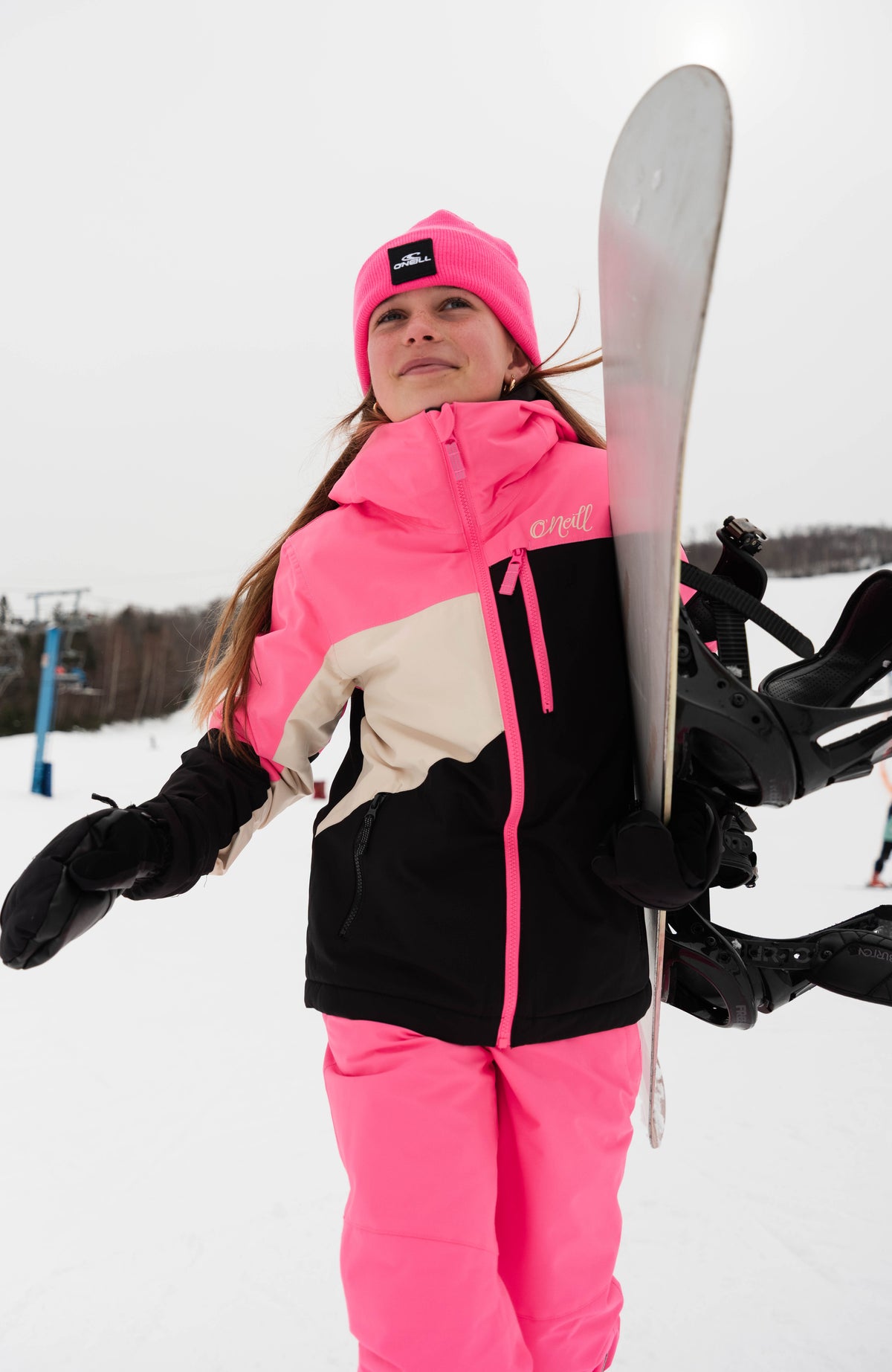 FWC'Cruz Triple Skijacke für Mädchen, schwarz, im Schnee getragen am Model mit Snowboard und Kapuze