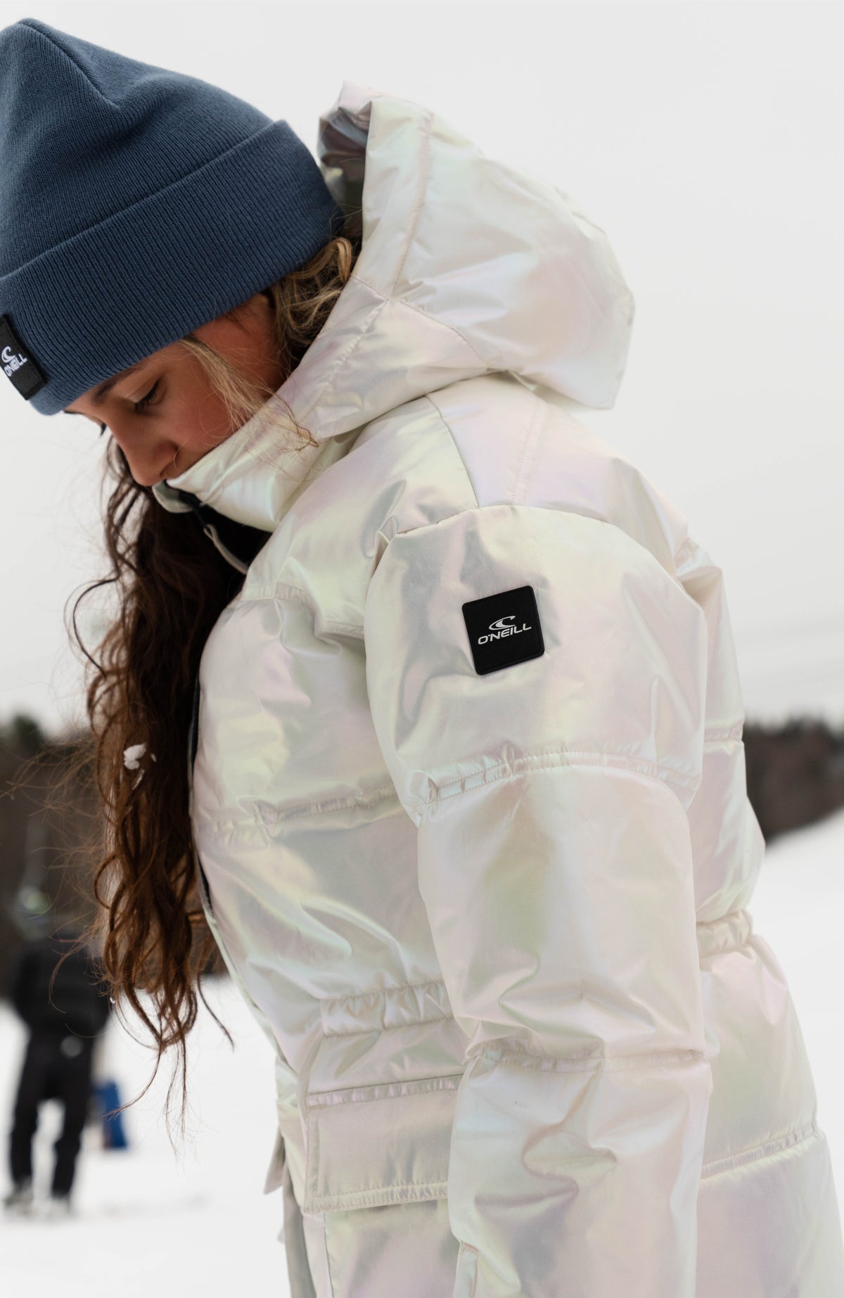Gesteppte FWC'Cruz Skijacke für Mädchen, weiß, am Model im Schnee, Nahaufnahme des Ärmels mit Logo-Patch