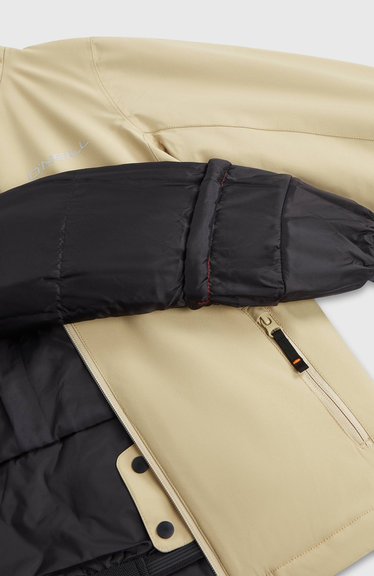 Nahaufnahme der beigen FWC'Cruz Skijacke für Mädchen, geöffnet mit schwarzem Innenfutter und Ärmeldetail