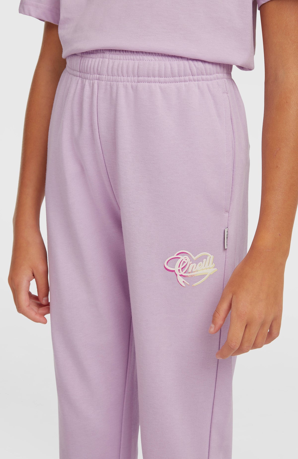 Essentials Script Jogginghose für Mädchen, lila, Nahaufnahme am Model mit elastischem Bund und Logo-Print