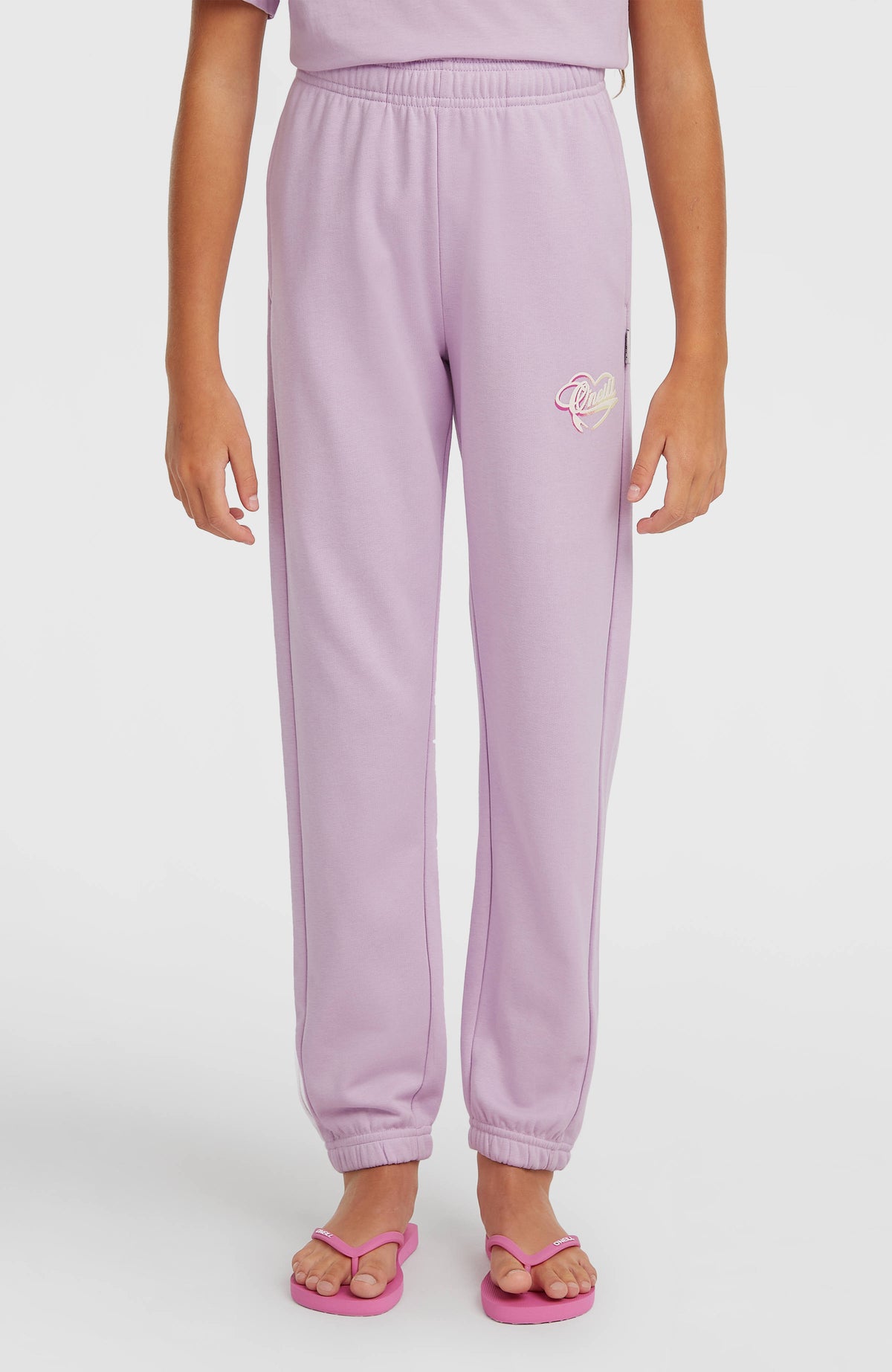 Essentials Script Jogginghose für Mädchen, lila, Vorderansicht am Model mit elastischen Beinabschlüssen