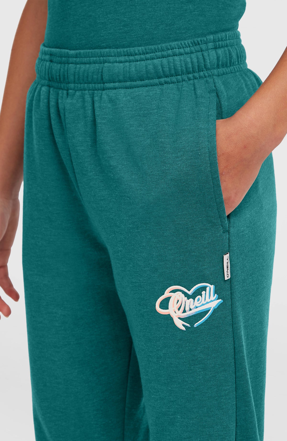 Essentials Script Jogginghose für Mädchen, grün, Nahaufnahme am Model mit Seitentasche und Herz-Logo-Print