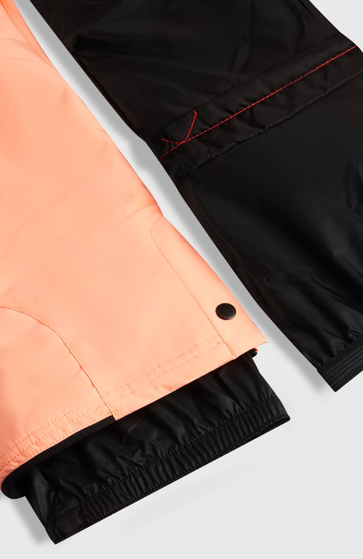 Nahaufnahme des Beinabschlusses mit Schneefang der orangen FWC'Cruz Skihose