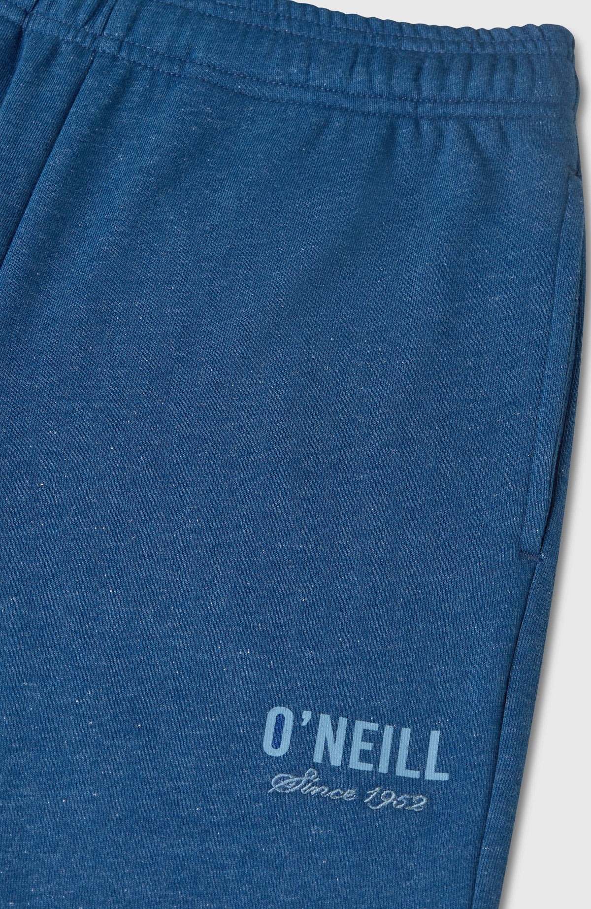 Nahaufnahme der blauen Essentials Jogginghose für Mädchen mit seitlicher Tasche und Logo-Schriftzug