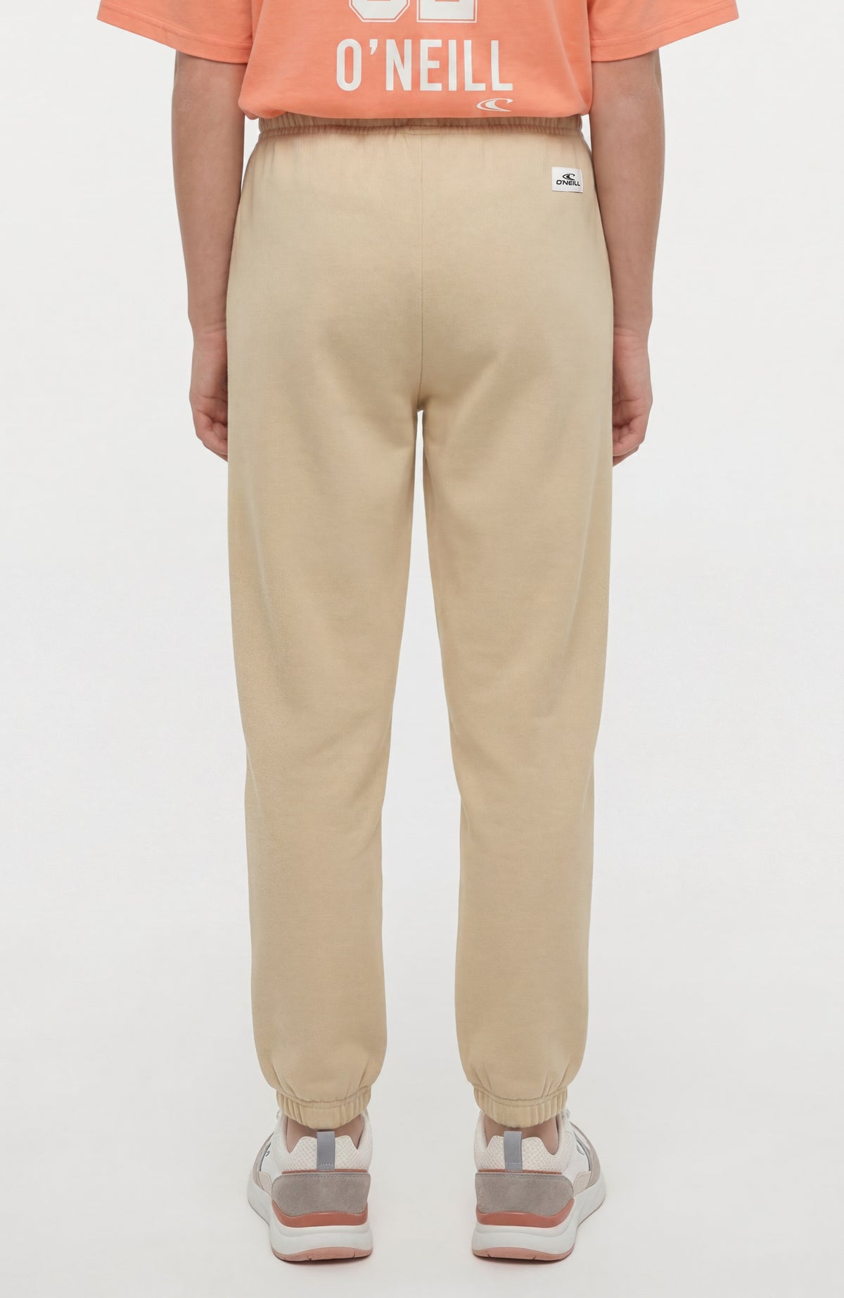 Essentials Jogginghose für Mädchen, beige, Rückansicht am Model mit kleinem Logo-Patch am Bund