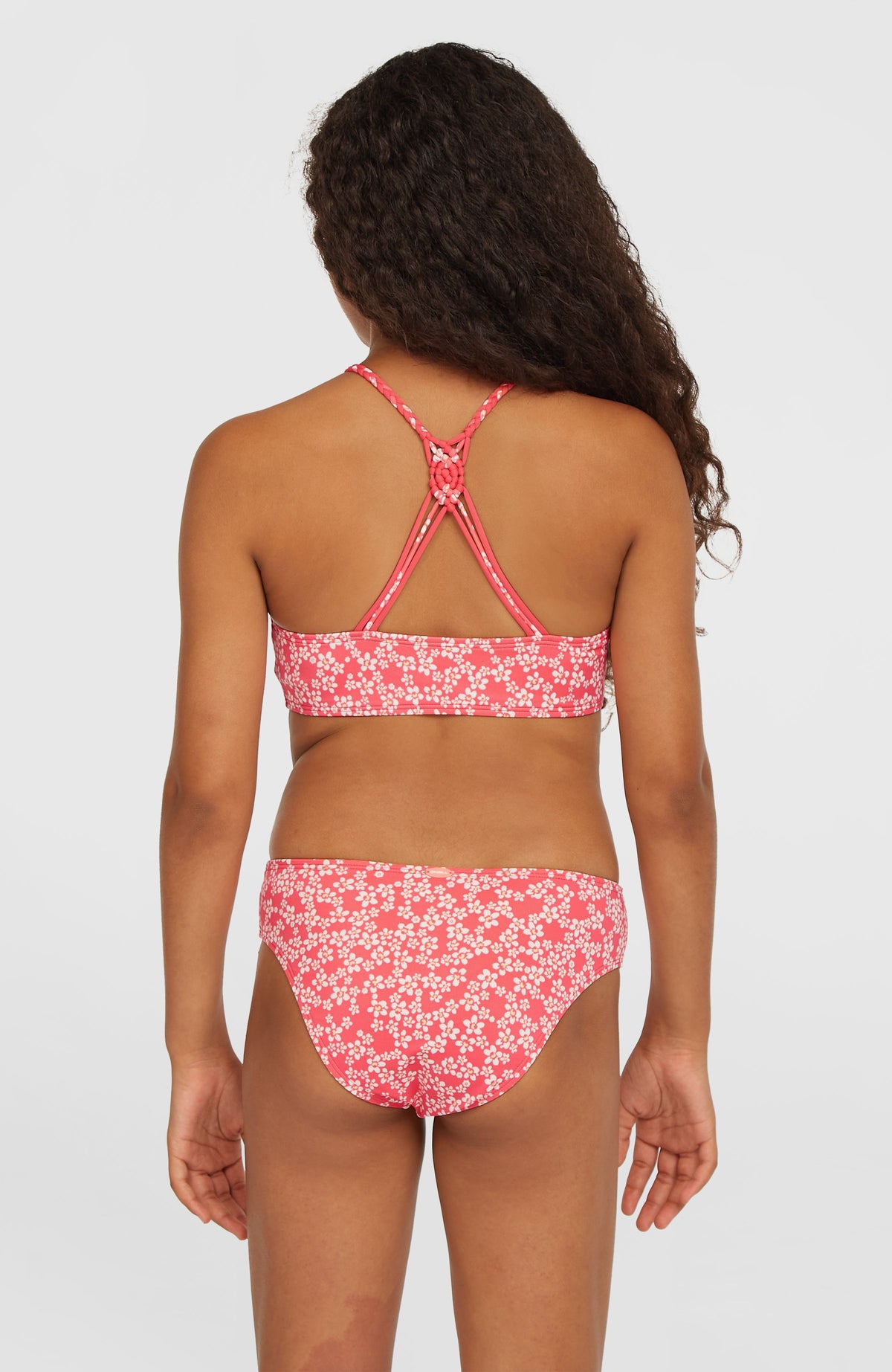 Tropics Bikini-Set für Mädchen, pink mit Blumenmuster in Weiß, Rückansicht am Model mit gekreuzten Trägern