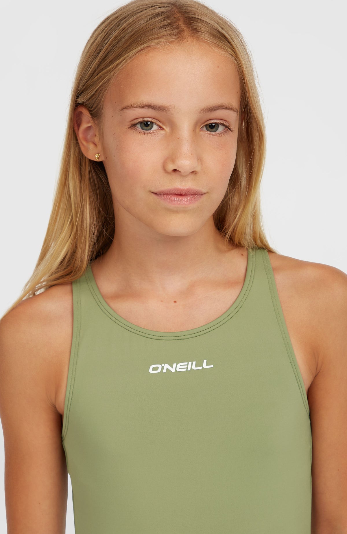 Essentials Badeanzug für Mädchen, grün, Nahaufnahme am Model mit weißem Logo-Schriftzug am Ausschnitt