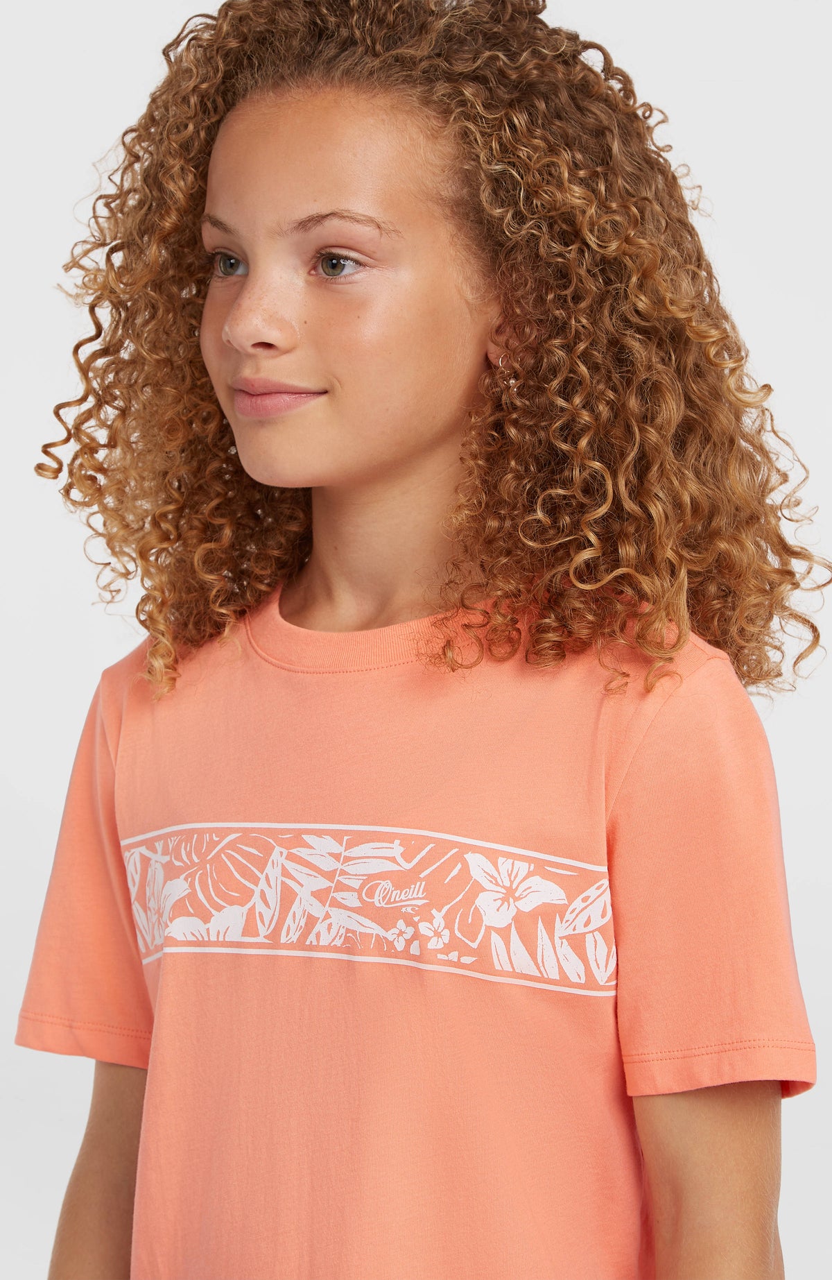 Graphic T-Shirt für Mädchen, orange mit Blumenmuster in Weiß, Nahaufnahme am Model mit Rundhalsausschnitt