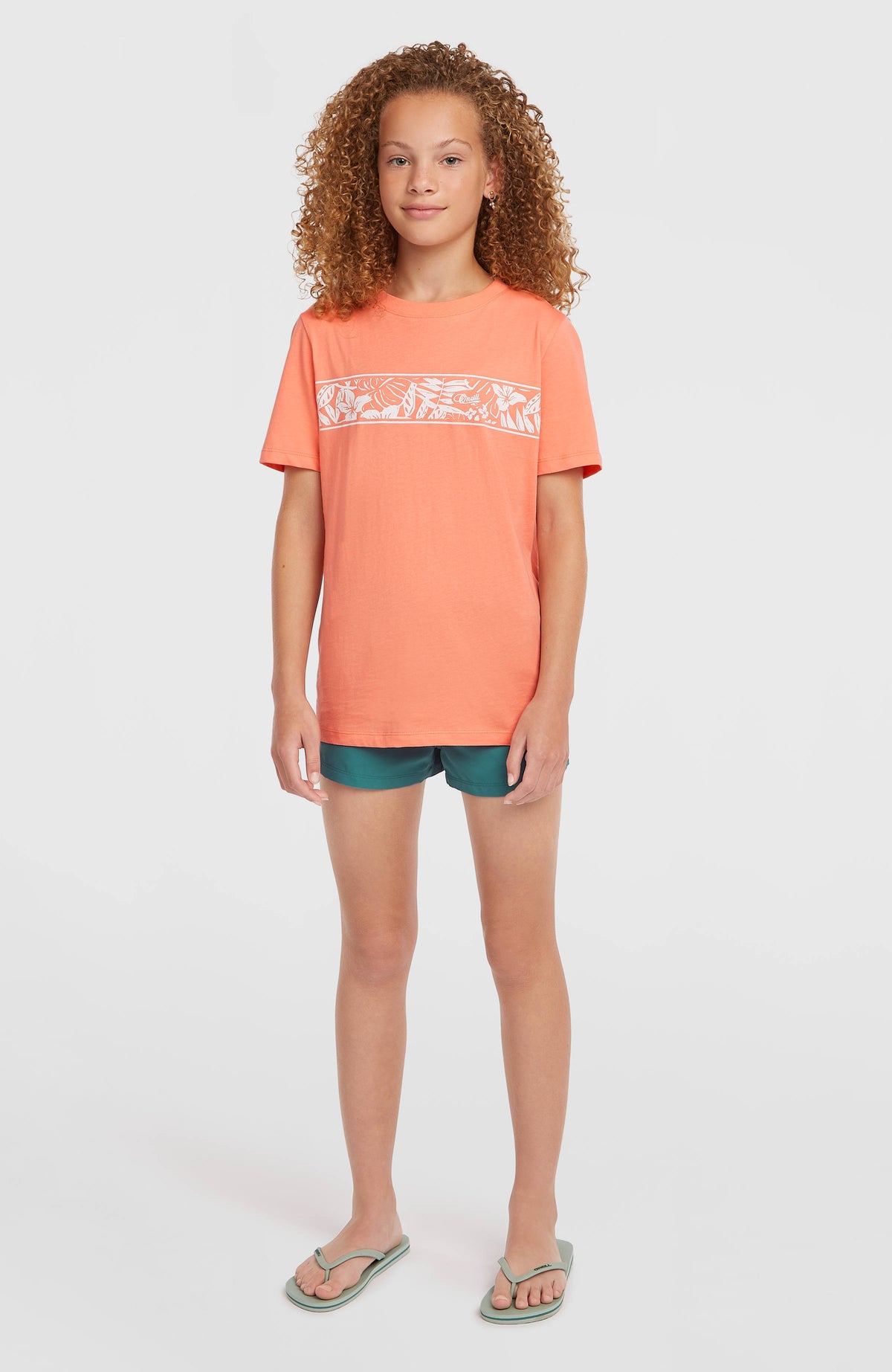 Graphic T-Shirt für Mädchen, orange mit Blumenmuster in Weiß, Vorderansicht in voller Länge am Model